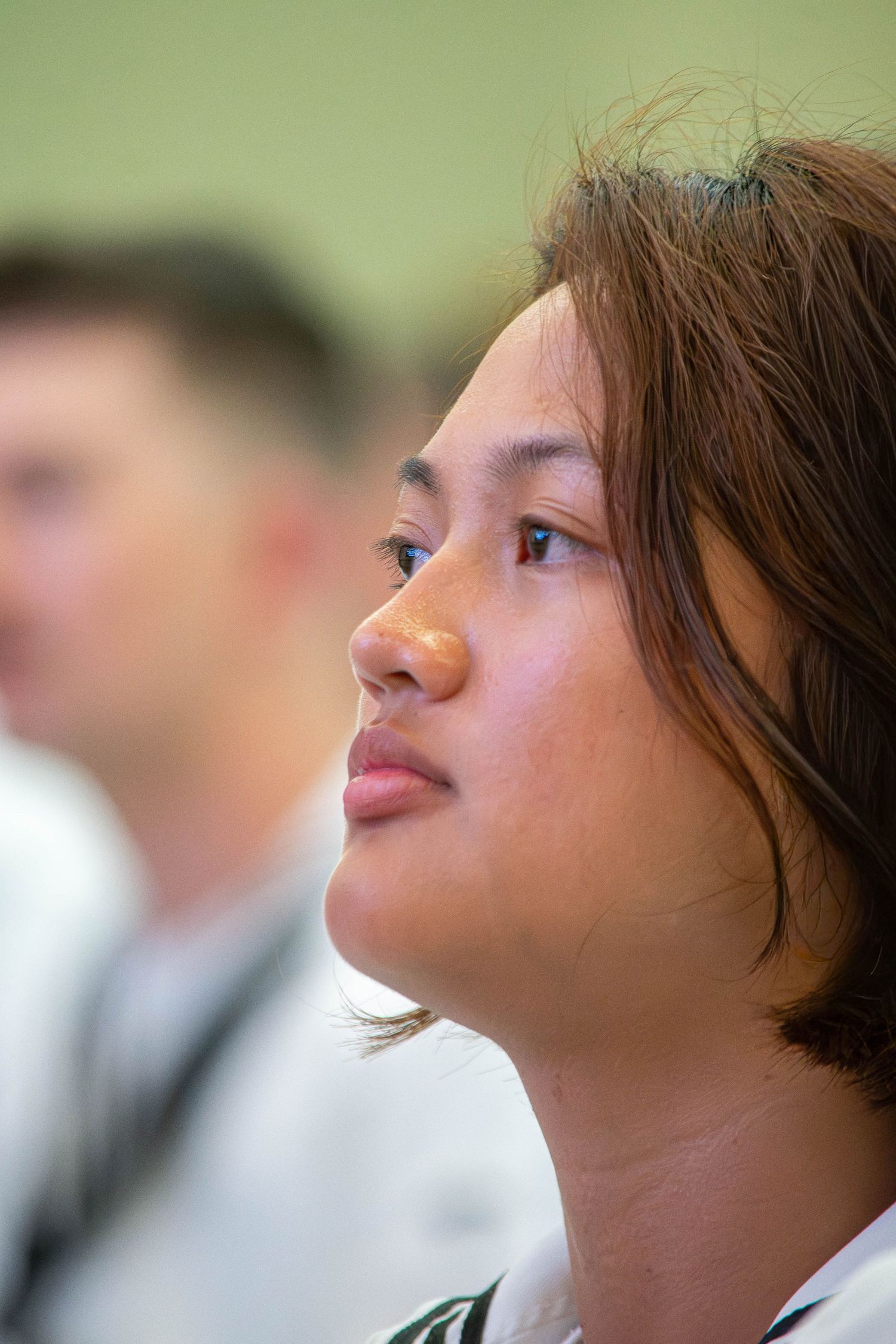 Young female Navy sailor in white uniform looking upward during a military ceremony.
