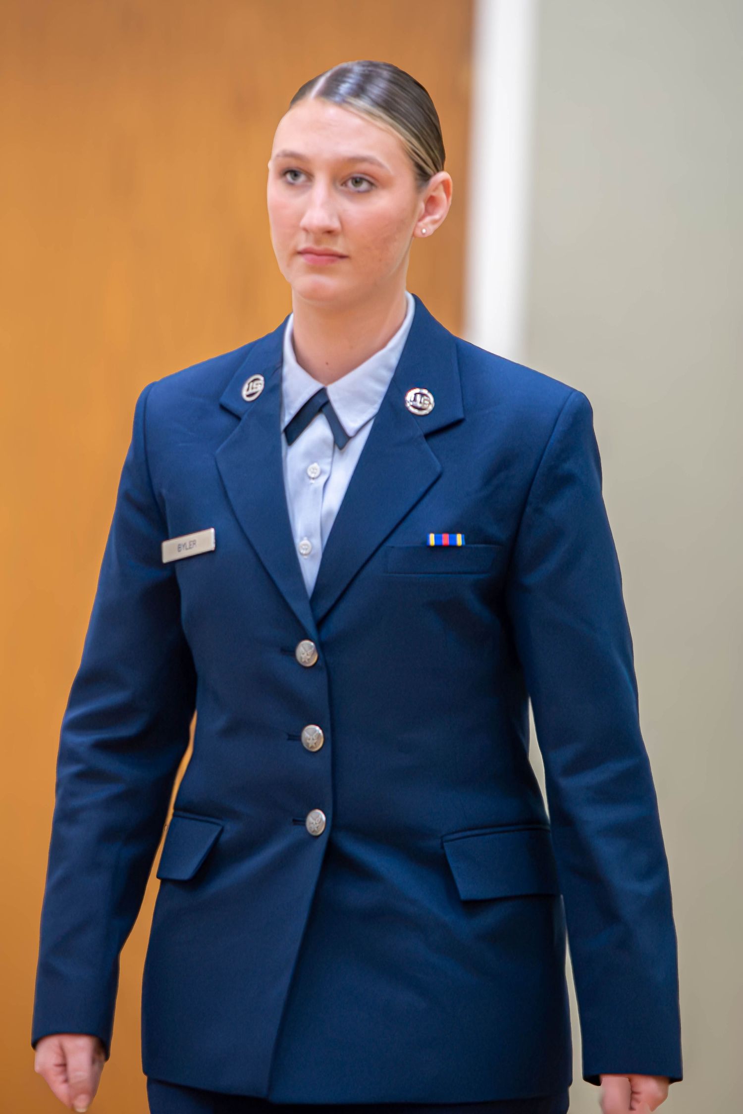 Young female US Air Force officer in dress blue uniform with service ribbons standing at attention.