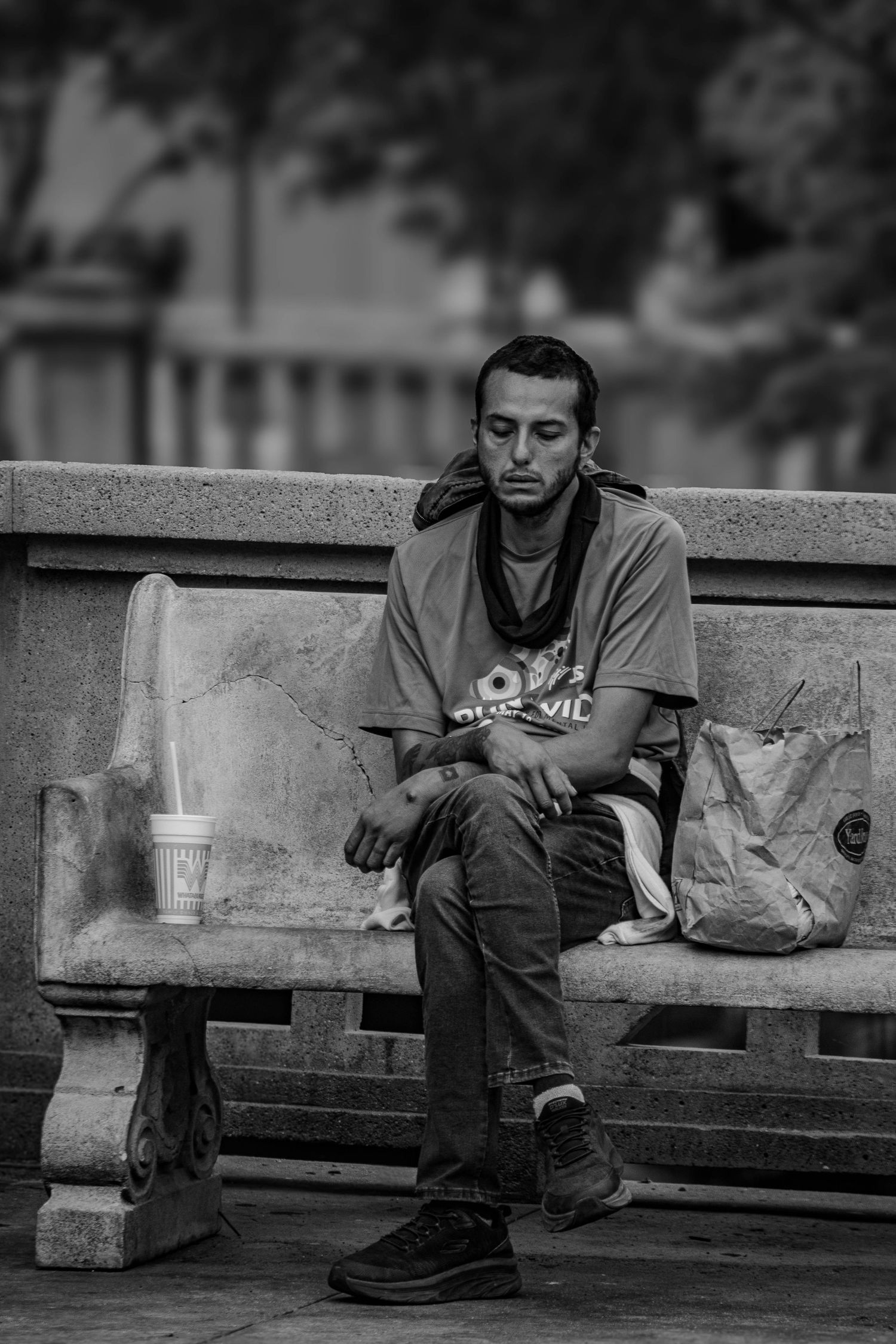 Young man sitting alone on a stone bench in black and white urban street photography.