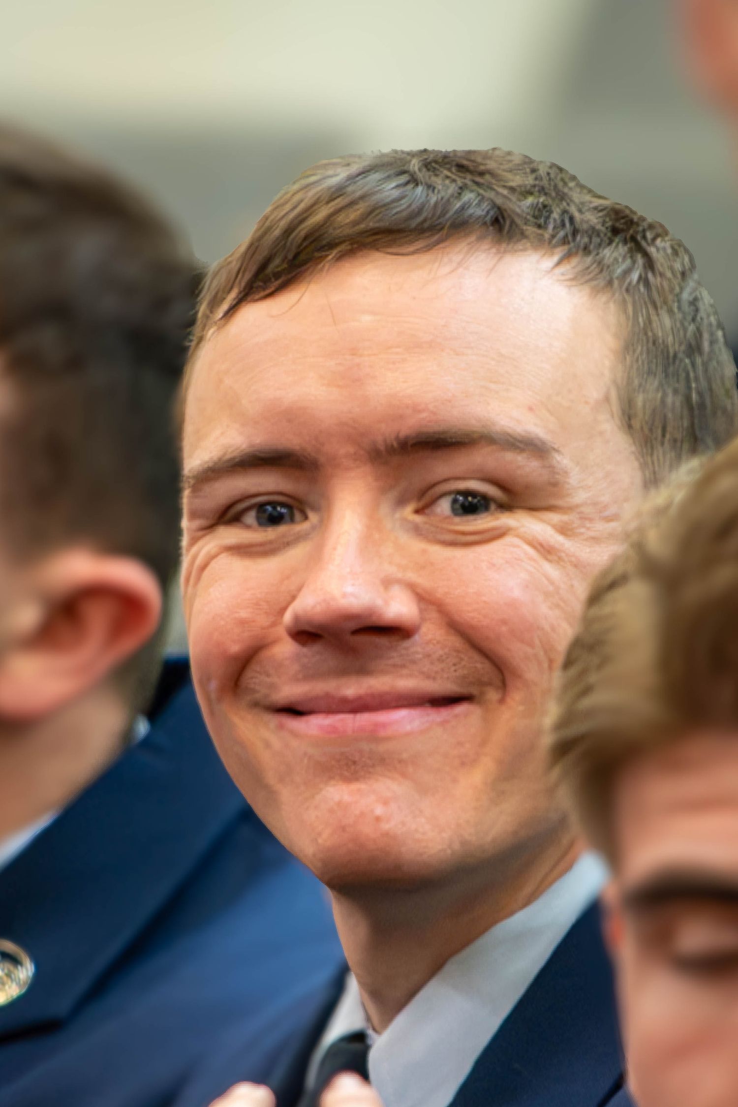 Young male Air Force cadet in blue uniform smiles candidly at camera.