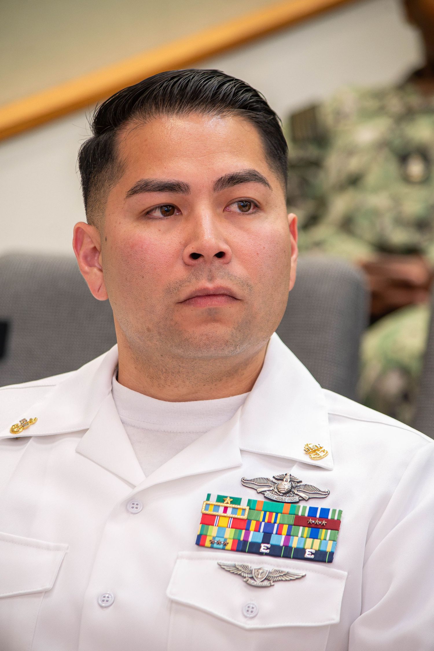 Male Navy officer in white dress uniform displaying medals and aviator wings.