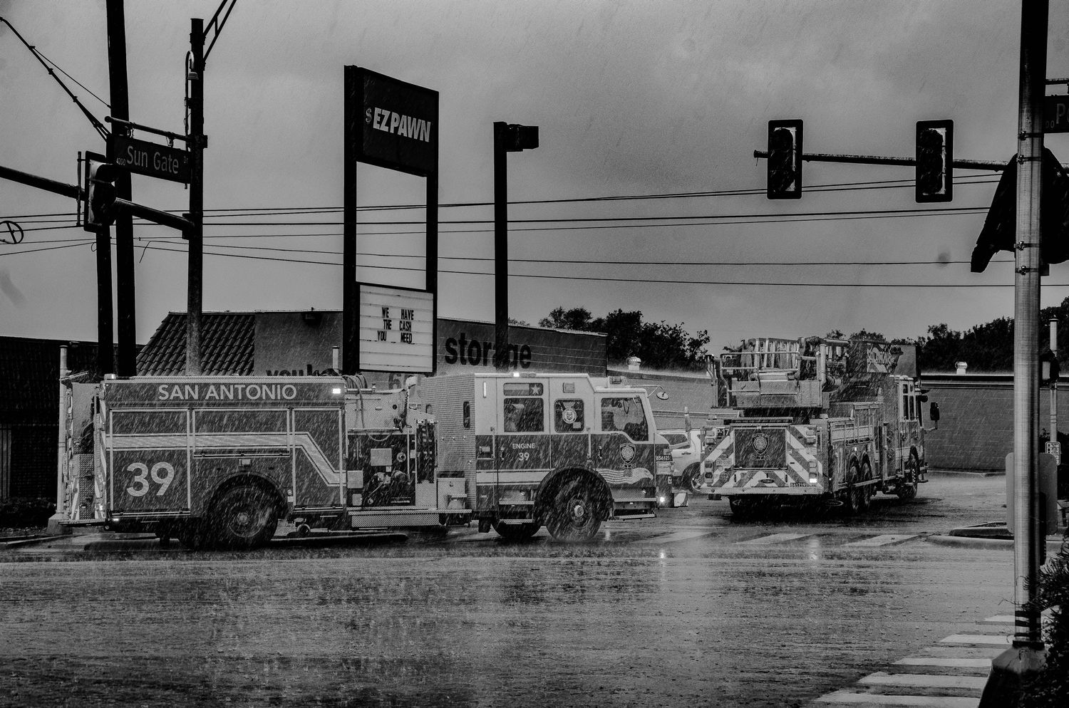 San Antonio Fire Department truck 39 responds to an emergency call in the rain at a busy intersection.