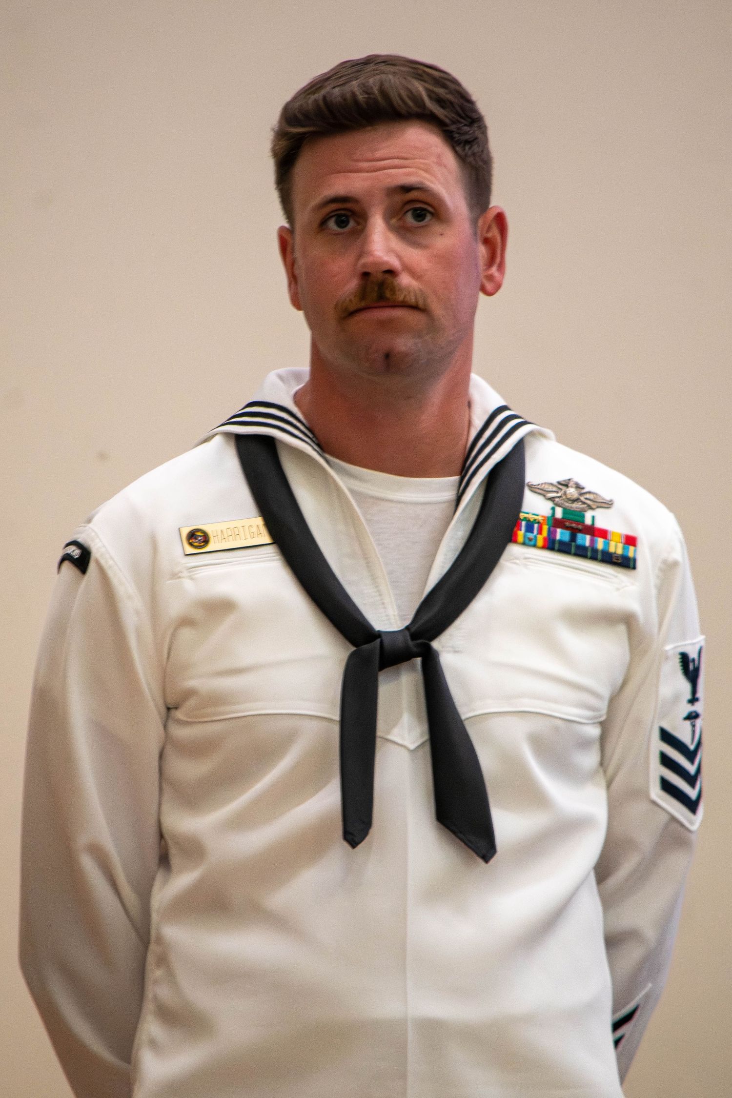 US Navy senior enlisted sailor in white dress uniform displaying medals and ribbons.