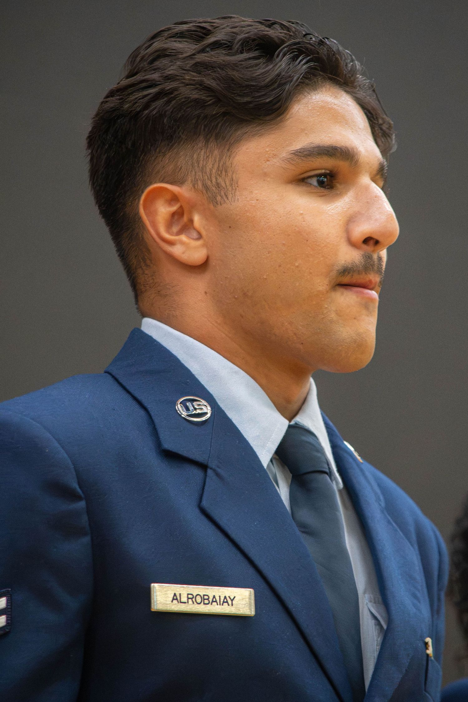 Male US Air Force airman named Alrobaiay in dress blue uniform with tie looking to the side.