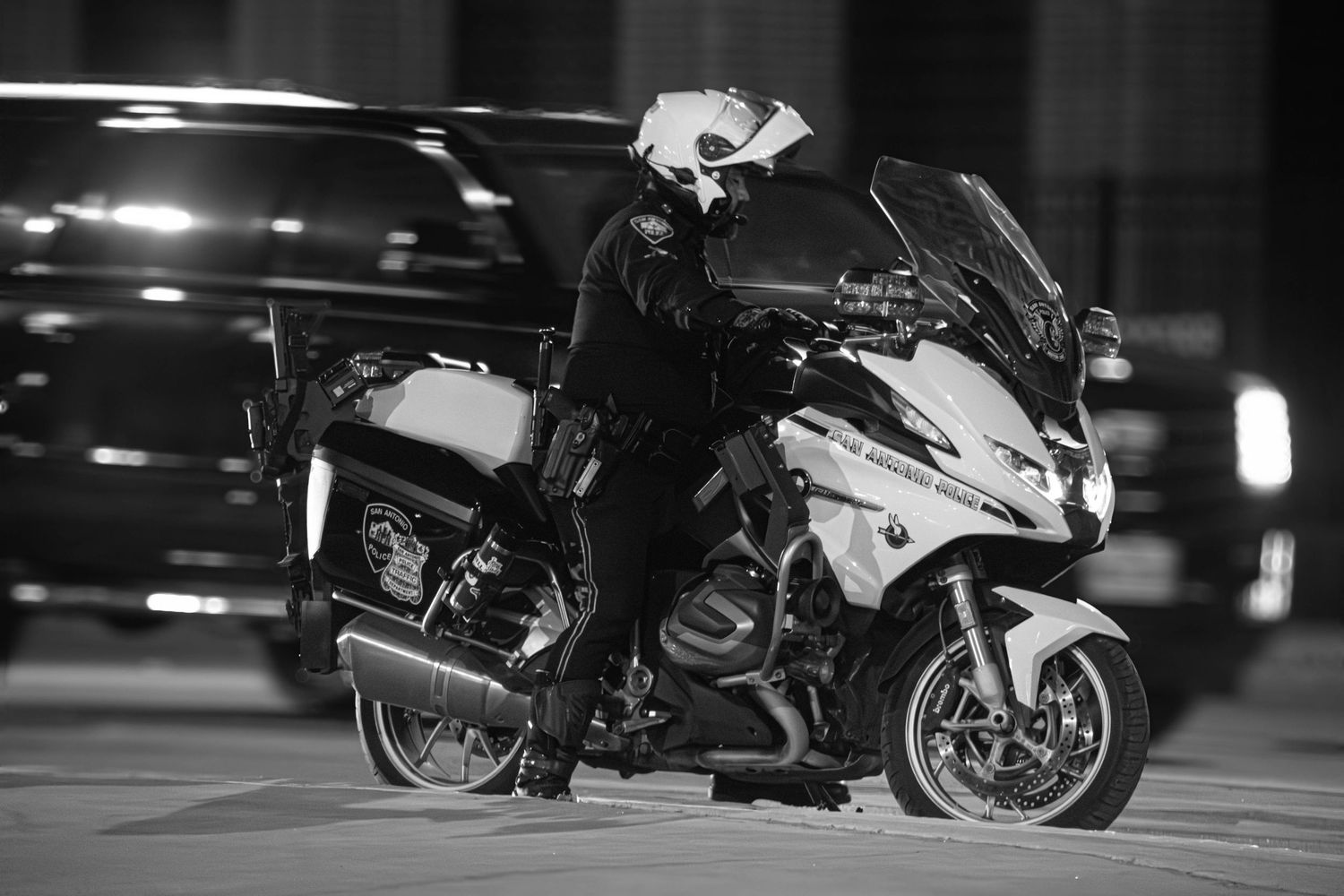 Black and white photo of a police officer on a BMW motorcycle at night.