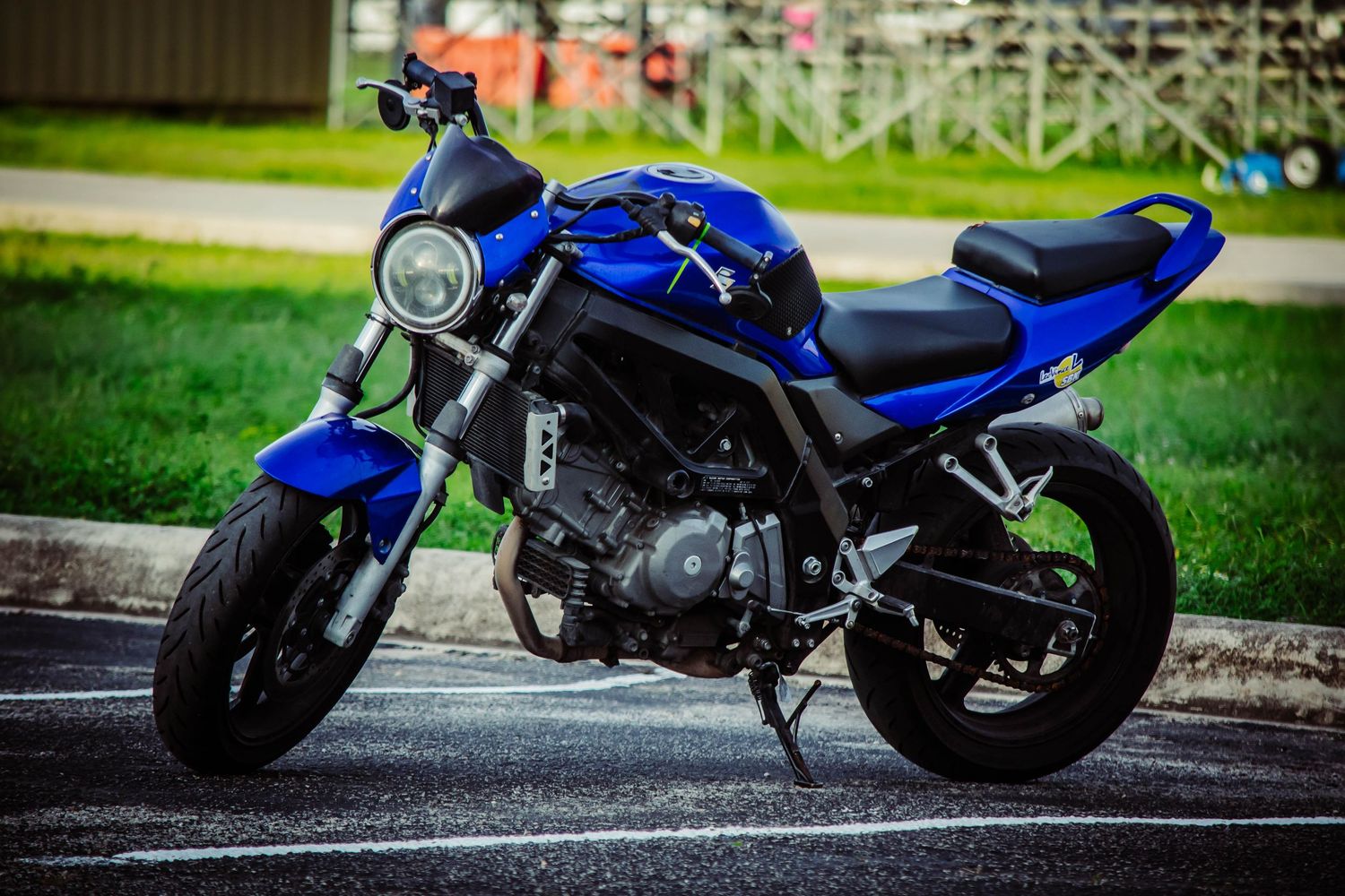 A sleek blue and black sport motorcycle parked on a paved surface with green grass in the background.