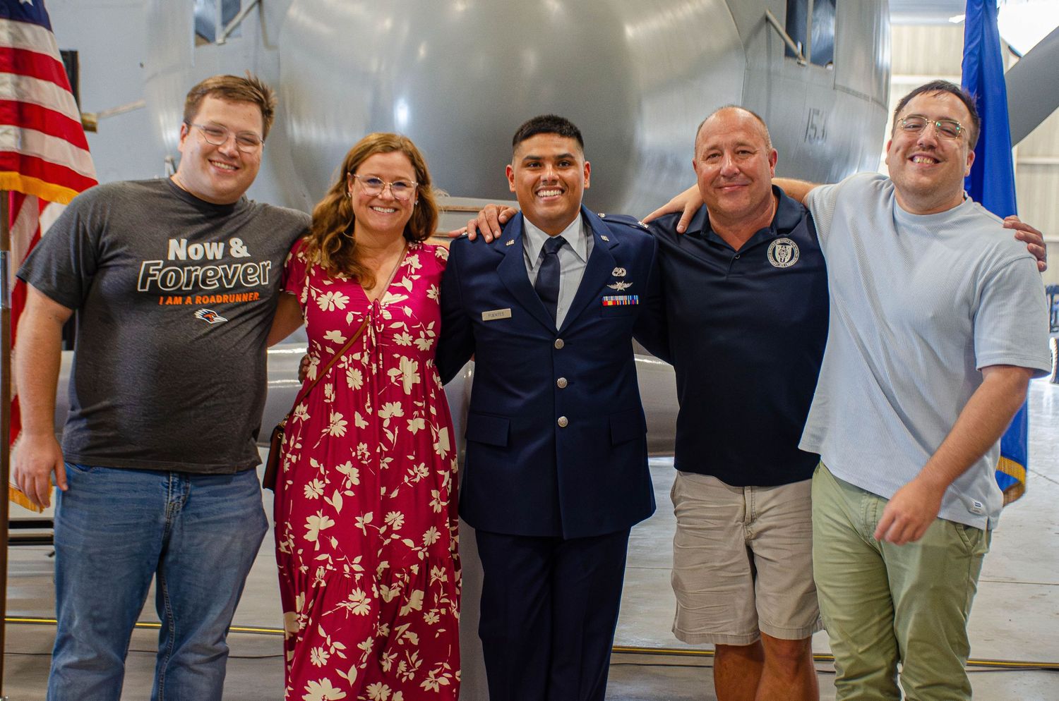 A US Air Force airman in dress uniform poses with four family members in front of a plane.
