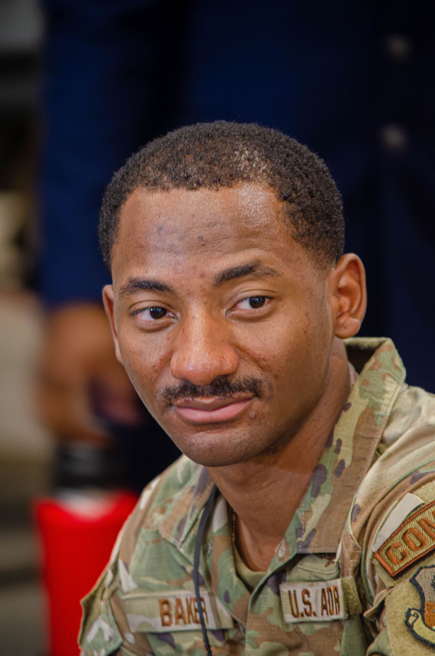 US Army soldier in camouflage uniform with Baker nameplate smiling during military service.