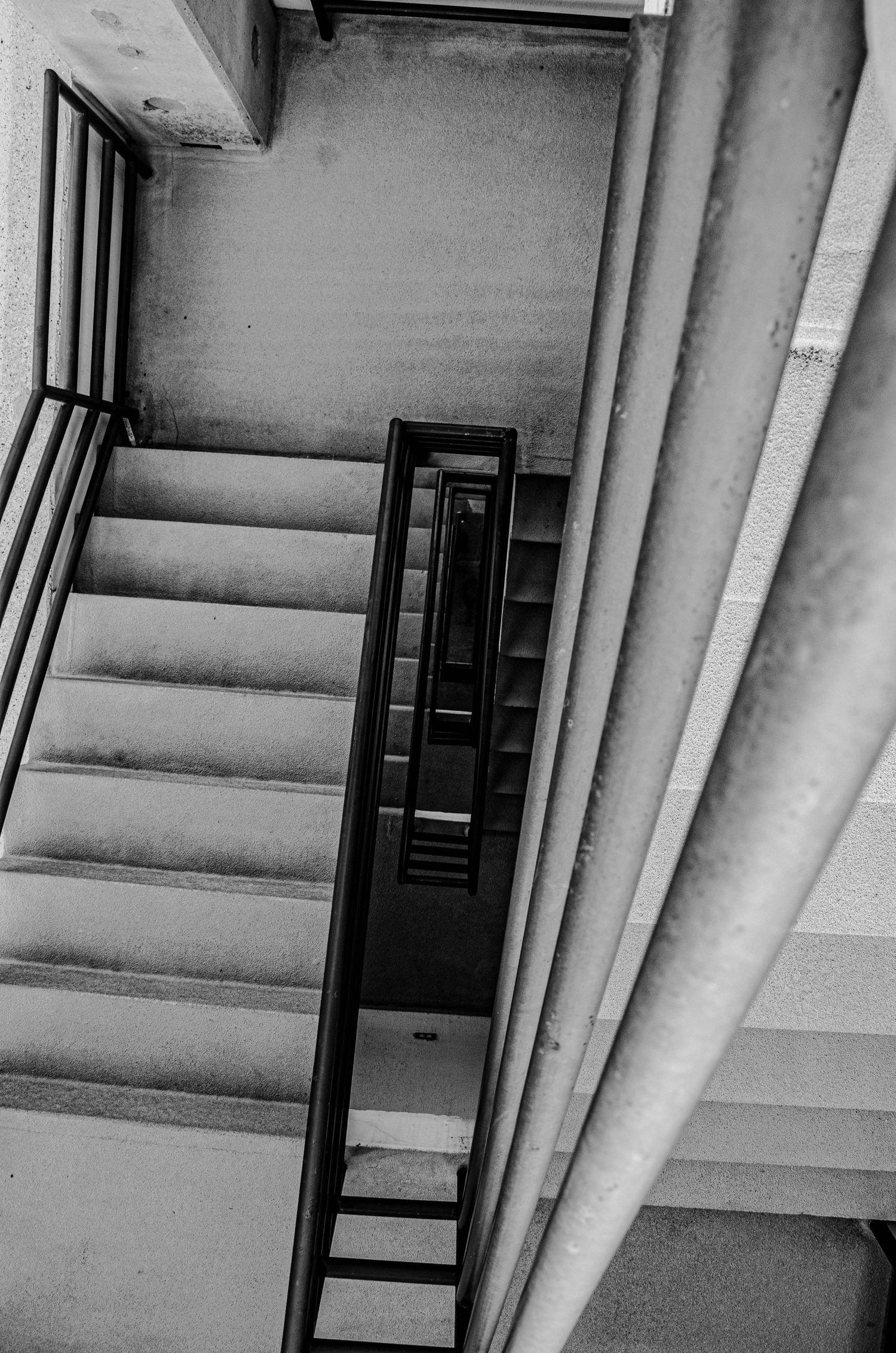 Black and white aerial view of interior staircase with metal railing in an urban building.