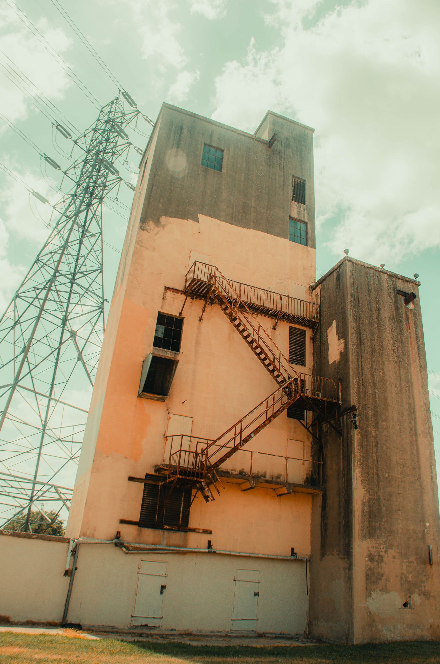 Vintage industrial building with rusty fire escape stairs and power tower.