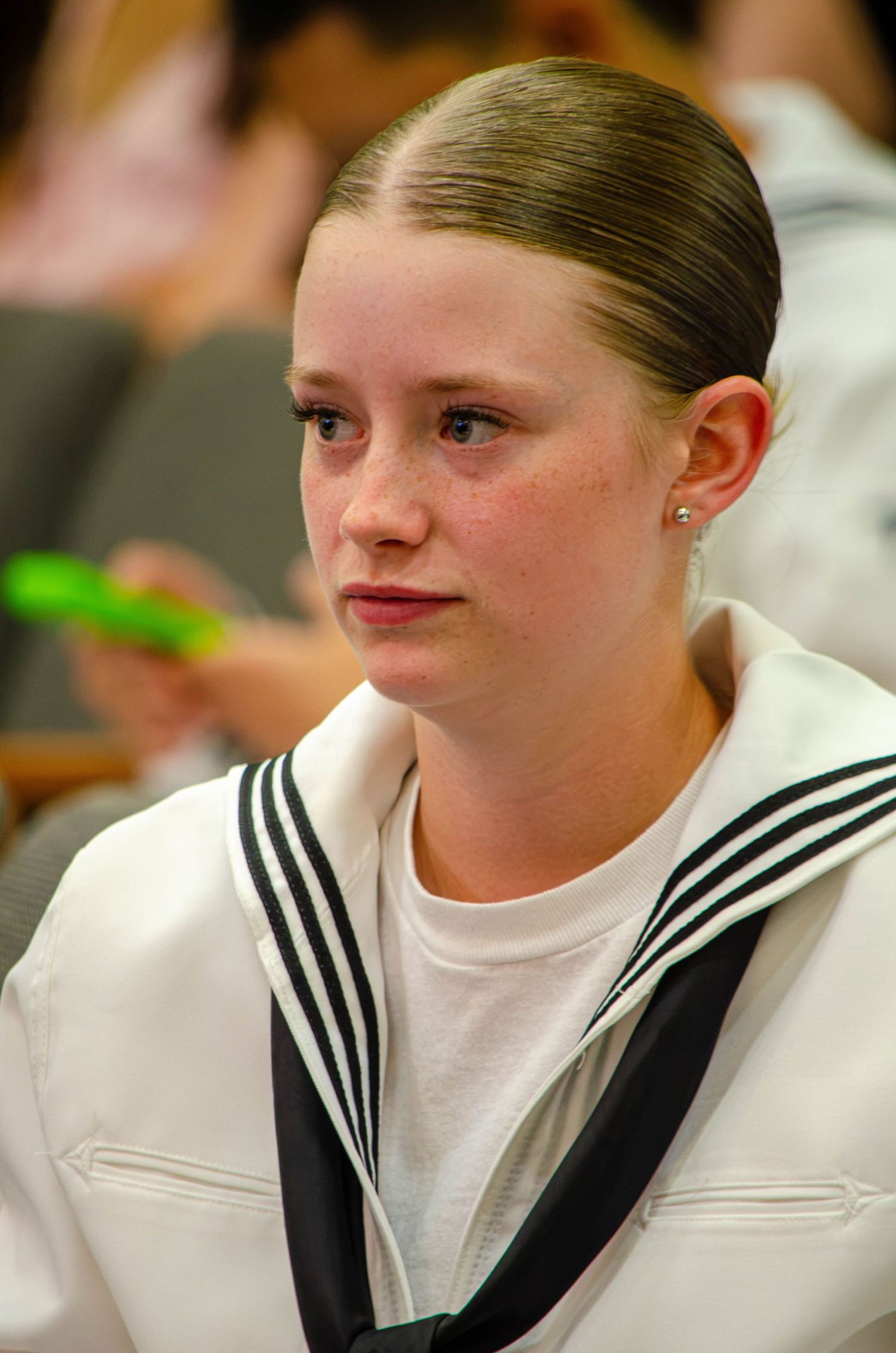 Young female Navy sailor in white uniform with black neckerchief at military ceremony.
