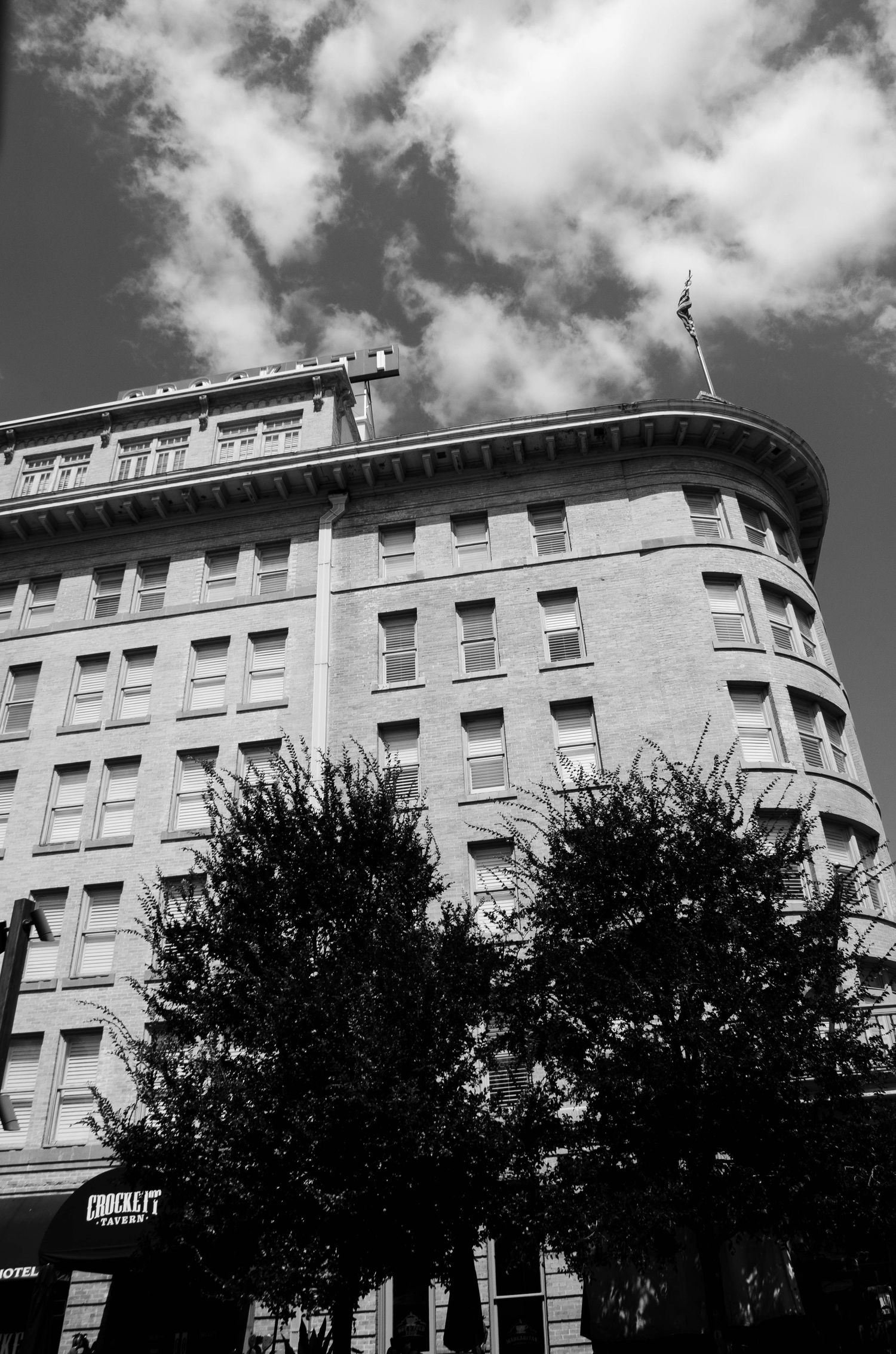 Historic multi-story brick building with ornate roofline in black and white.