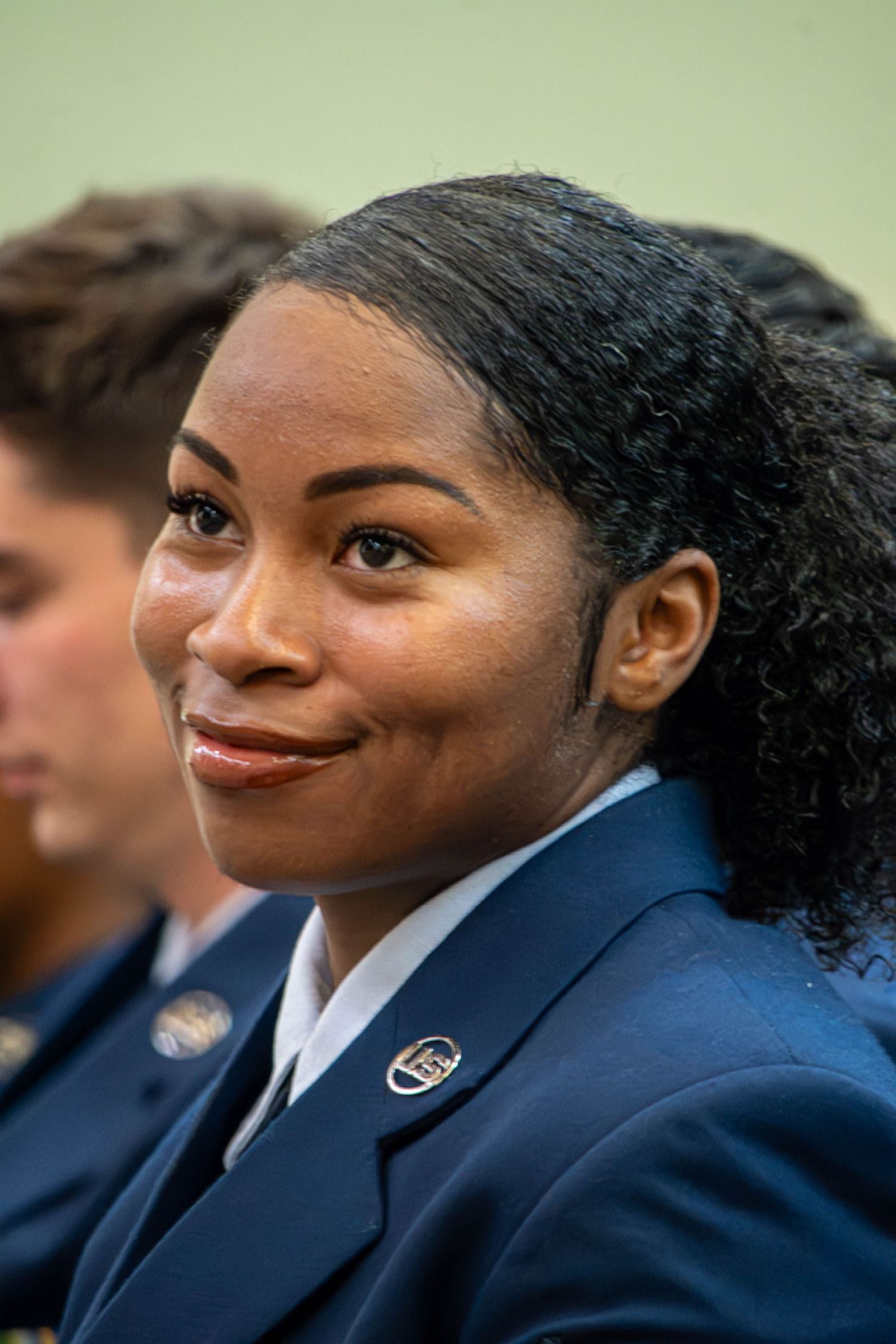 Smiling female US Air Force member in dress blue uniform with hair pulled back.