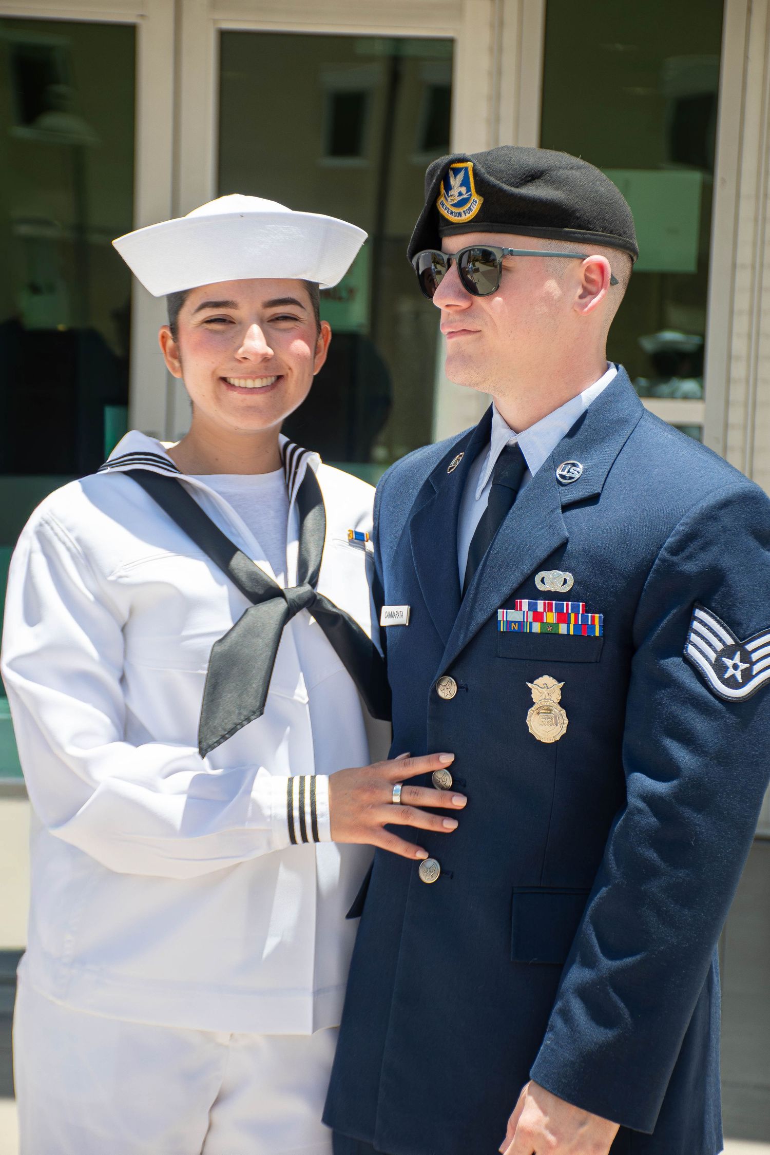 Female Navy sailor in dress whites poses with Air Force serviceman in uniform.