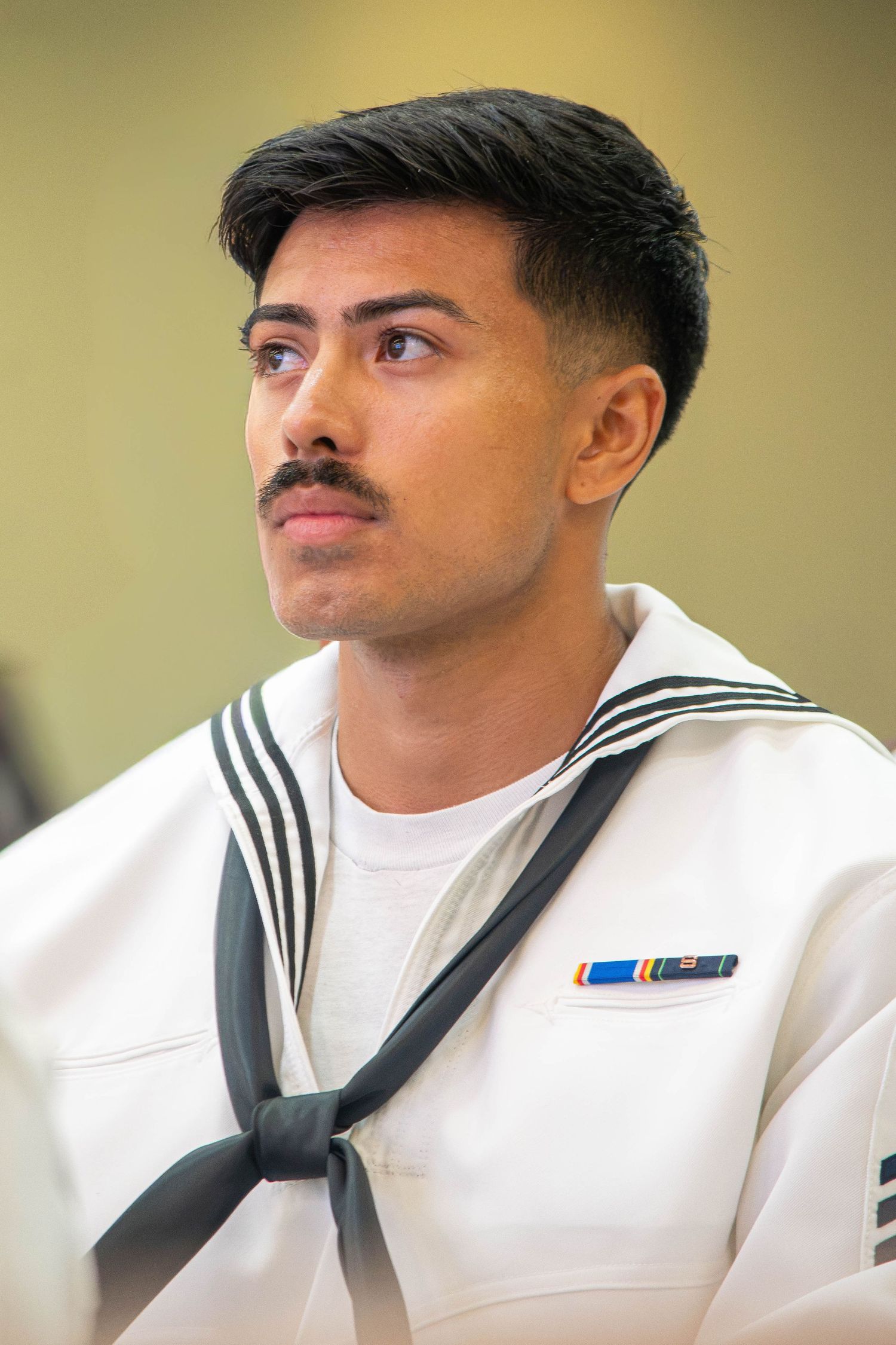 Male U.S. Navy sailor with ribbon award on white dress uniform at military graduation.