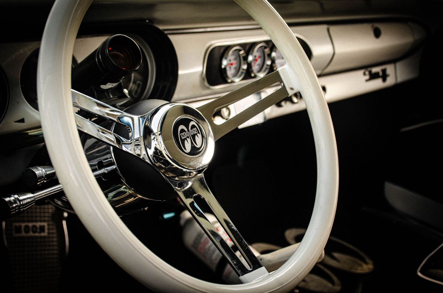 Vintage Ford Mustang interior featuring a classic white steering wheel with chrome accents and retro dashboard gauges.