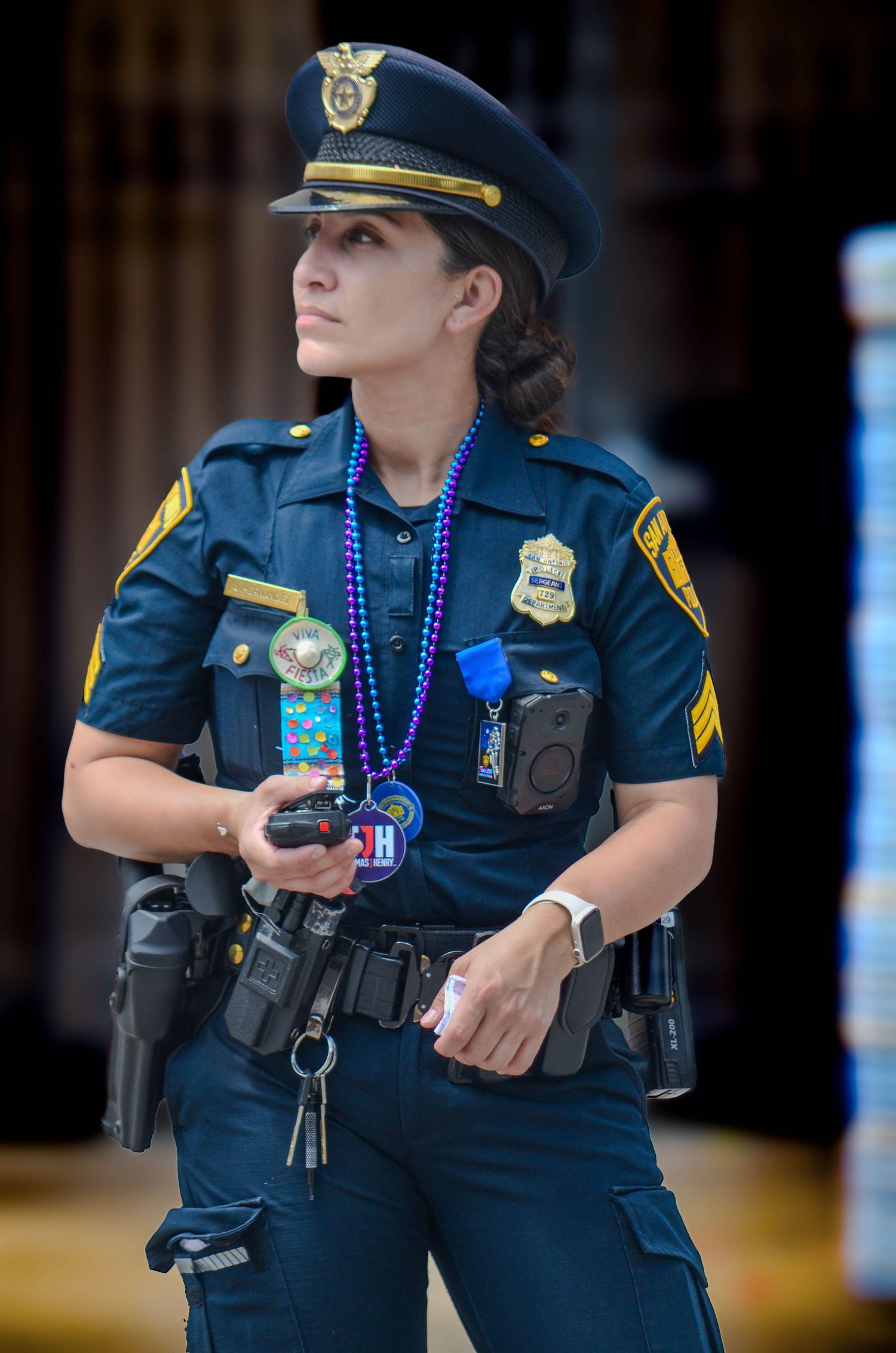 A female police officer in uniform wearing Mardi Gras beads while on duty outdoors.