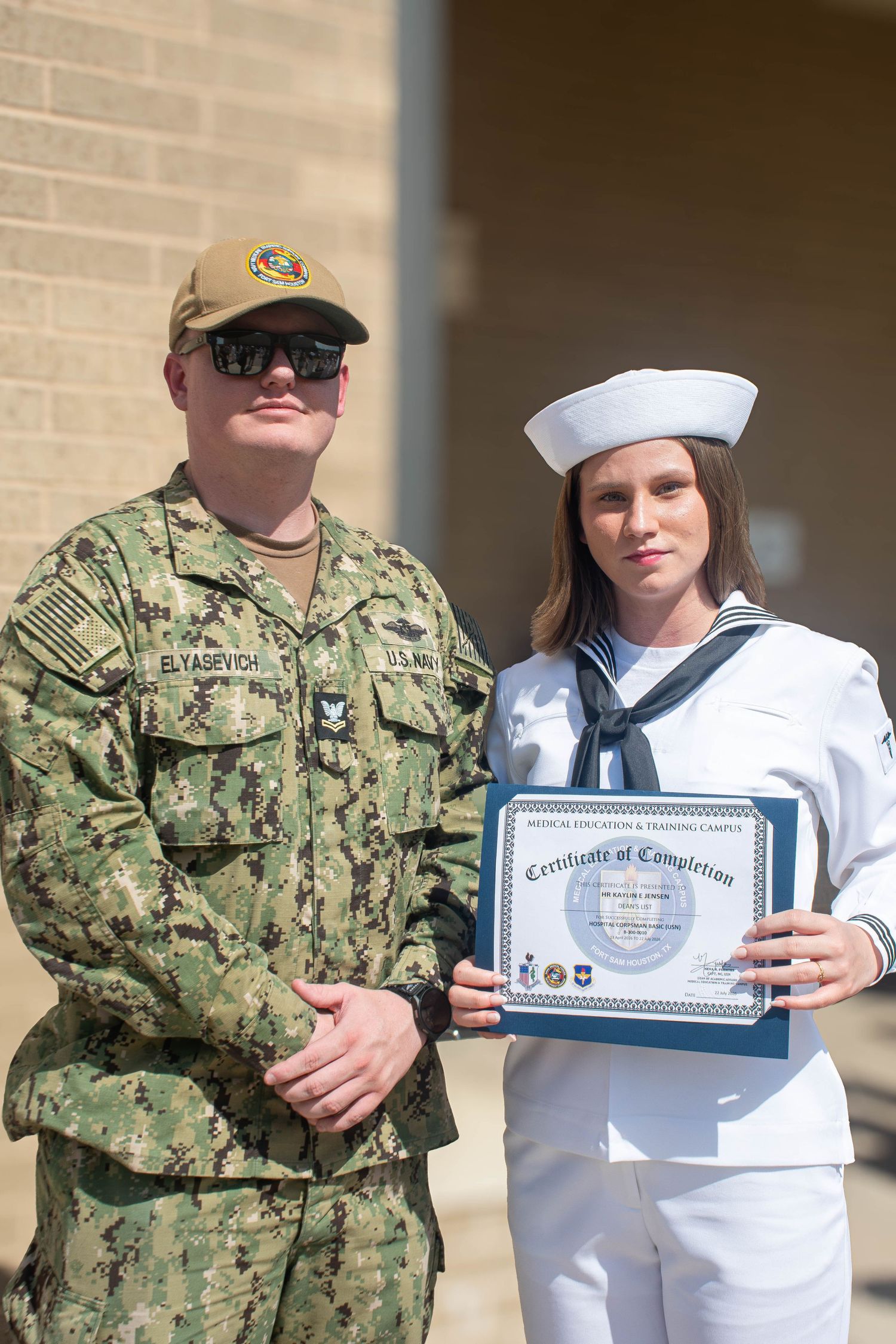 Navy sailor receives Certificate of Completion from uniformed military officer in camouflage at ceremony.