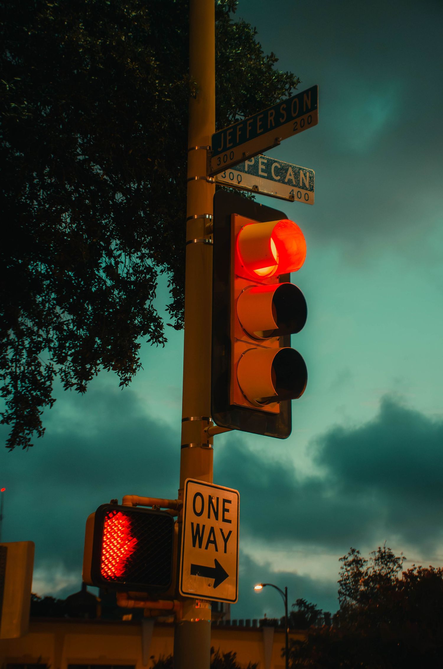 Red traffic light and One Way sign at Jefferson and Pecan Street intersection at dusk.
