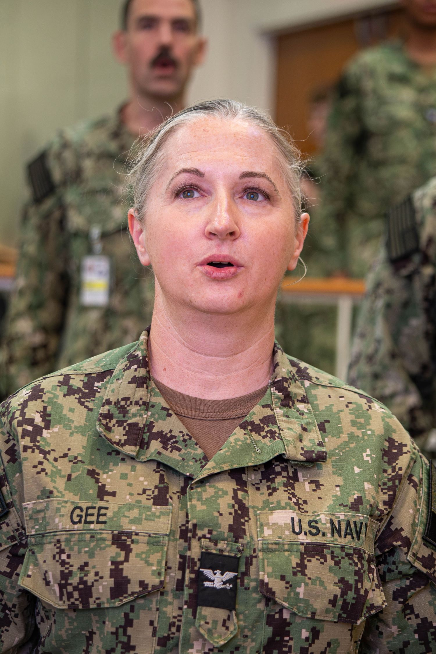 U.S. Navy Captain Gee in camouflage uniform speaks at a military briefing.