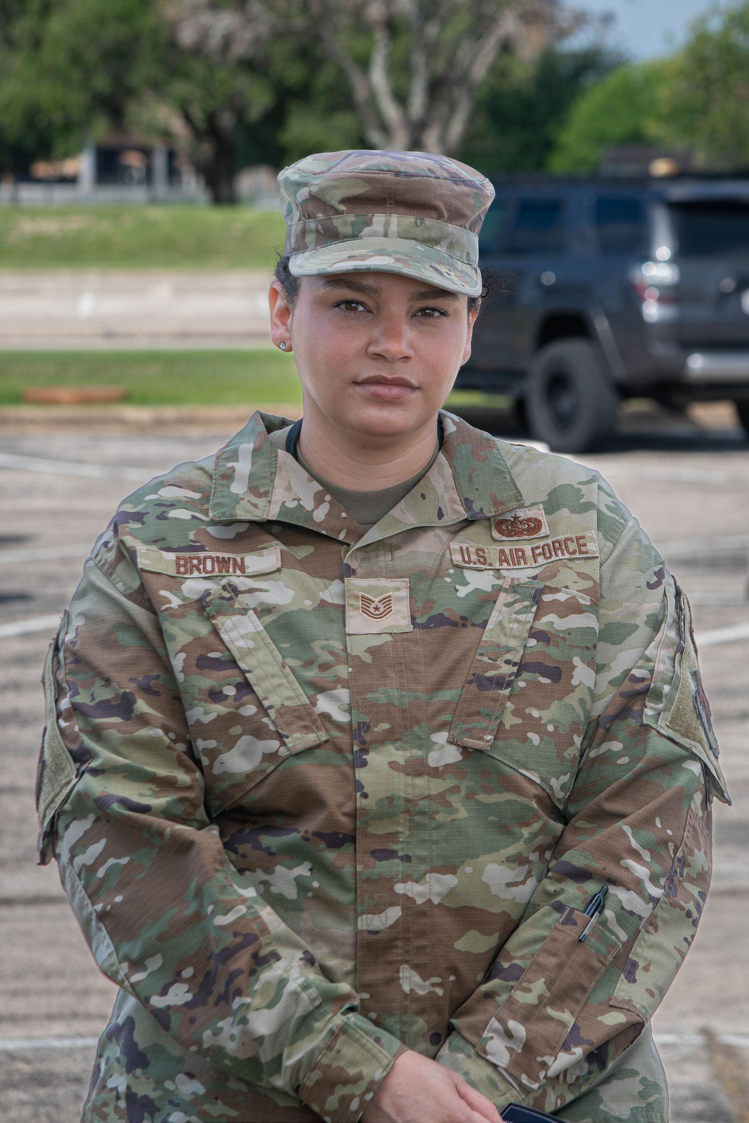 US Air Force soldier named Brown in camouflage uniform and cap standing outdoors on base.