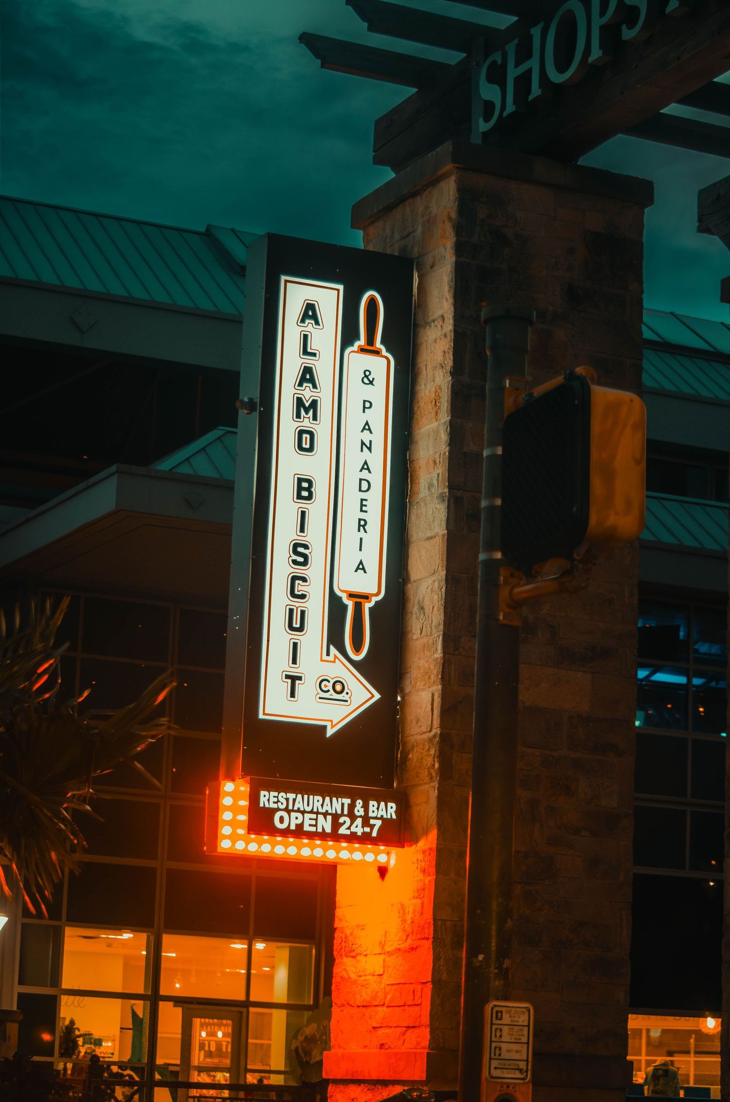 Alamo Biscuit Co and Panderia neon sign glowing at night outside a restaurant open 24-7.