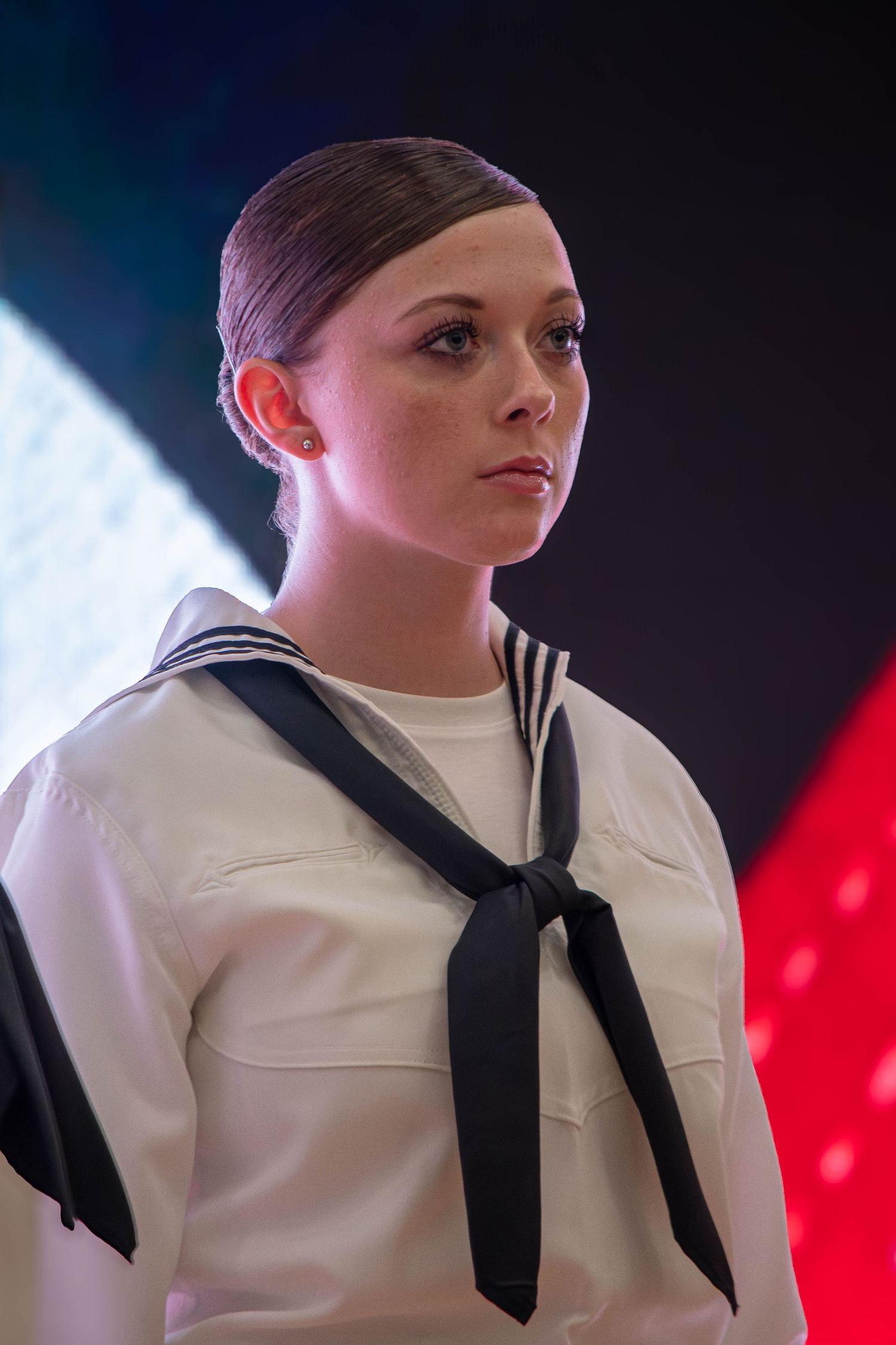US Navy sailor in white dress uniform with black neckerchief standing at formal attention.