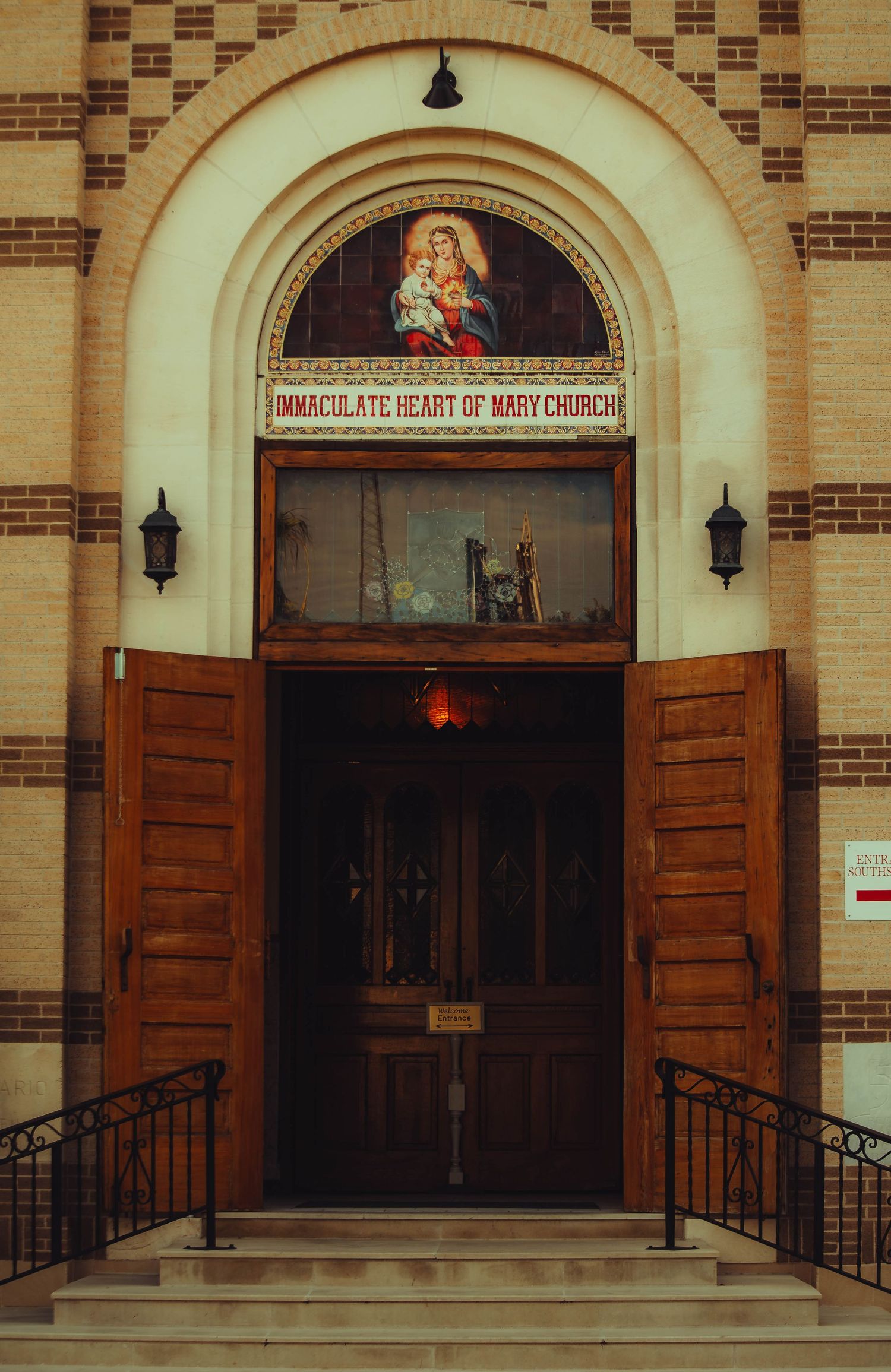 Entrance to Immaculate Heart of Mary Church with ornate wooden doors and religious artwork above.