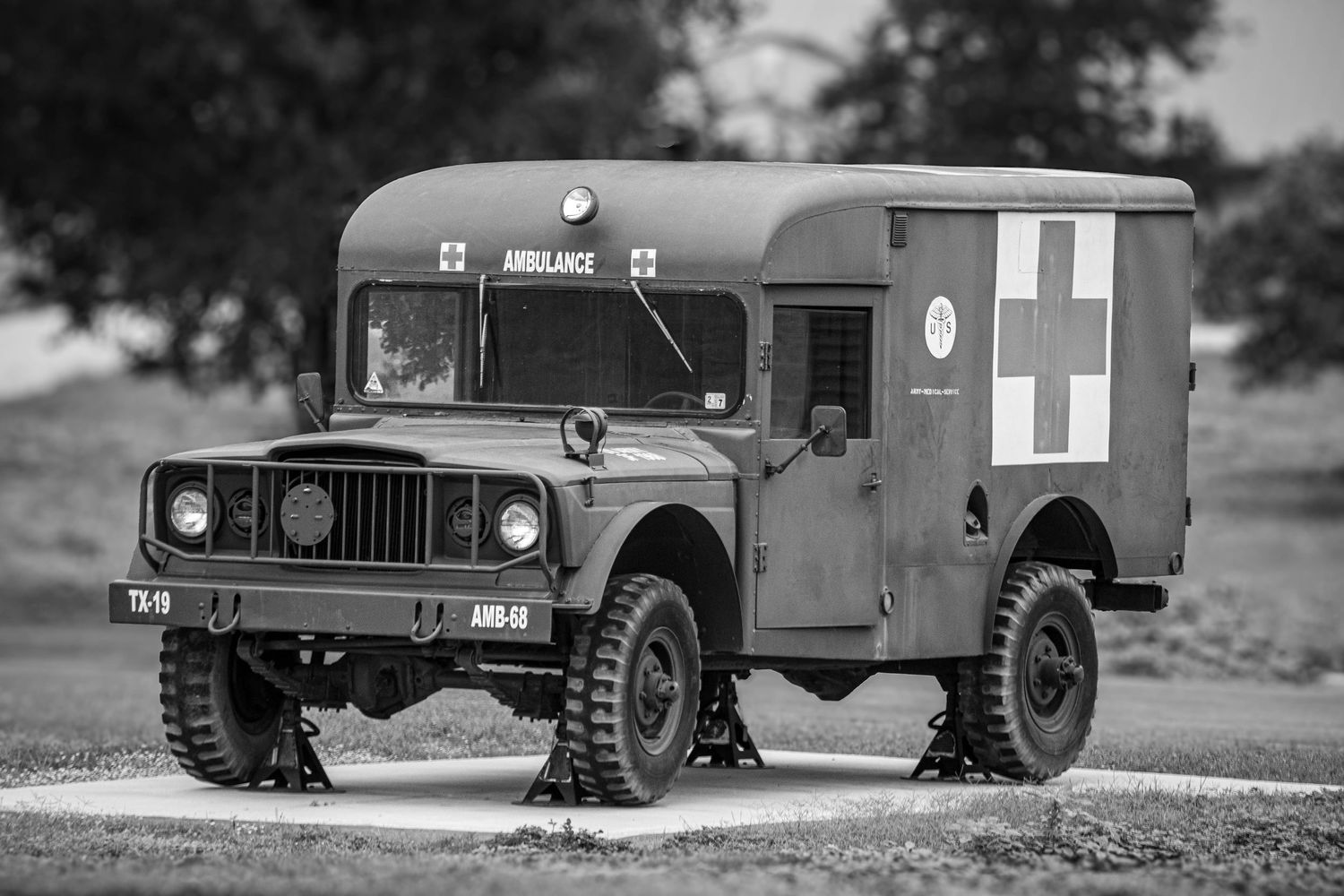 Vintage military ambulance truck with cross markings parked outdoors, captured in black and white photography.