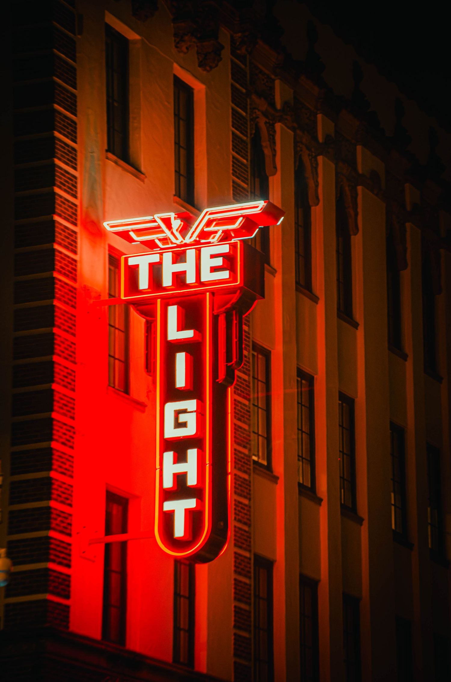 Glowing red neon sign reading The Light on a brick building at night.