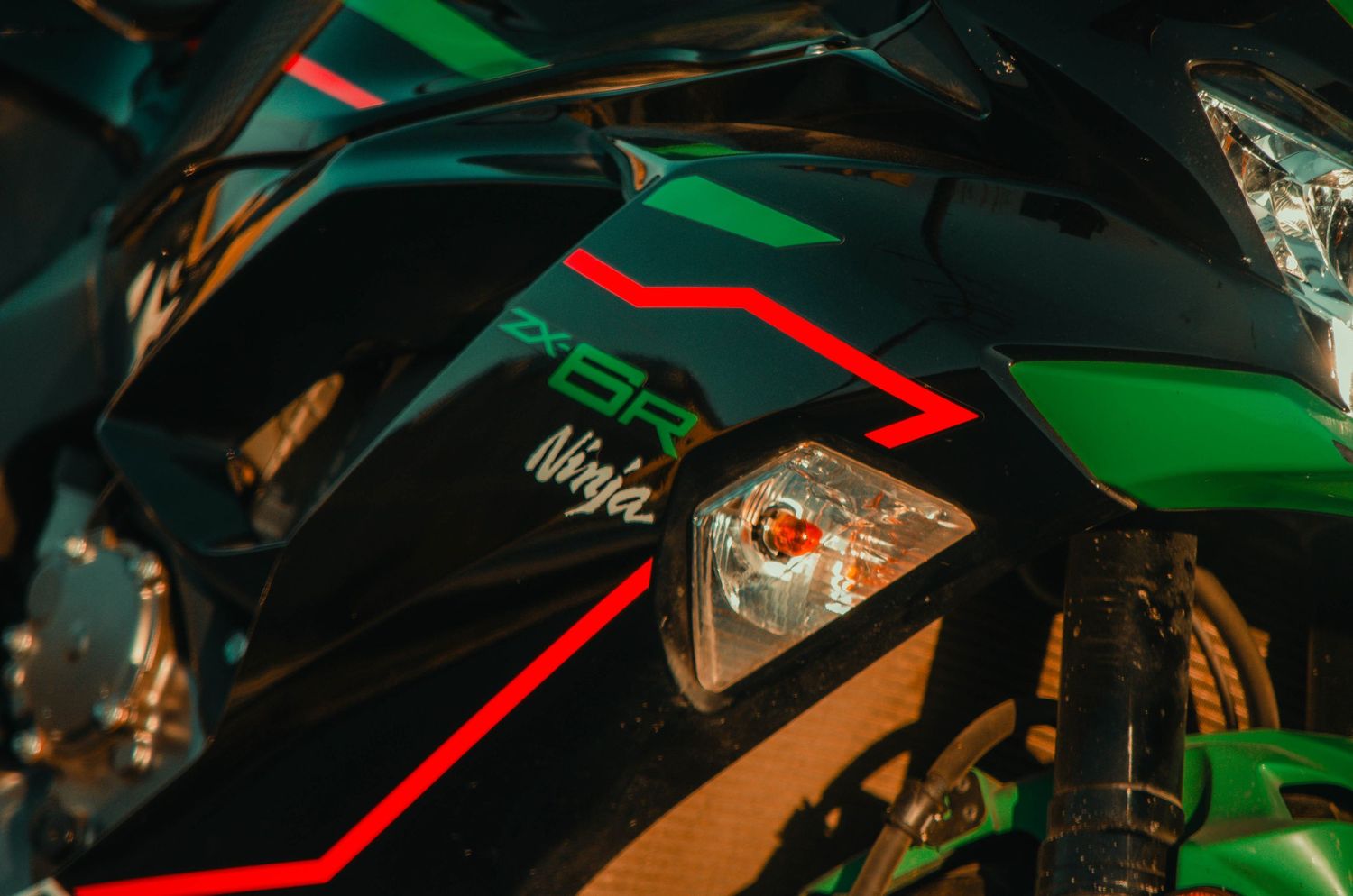 Close-up of a Kawasaki Ninja motorcycle fairing in black and green with red accents and turn signal light.