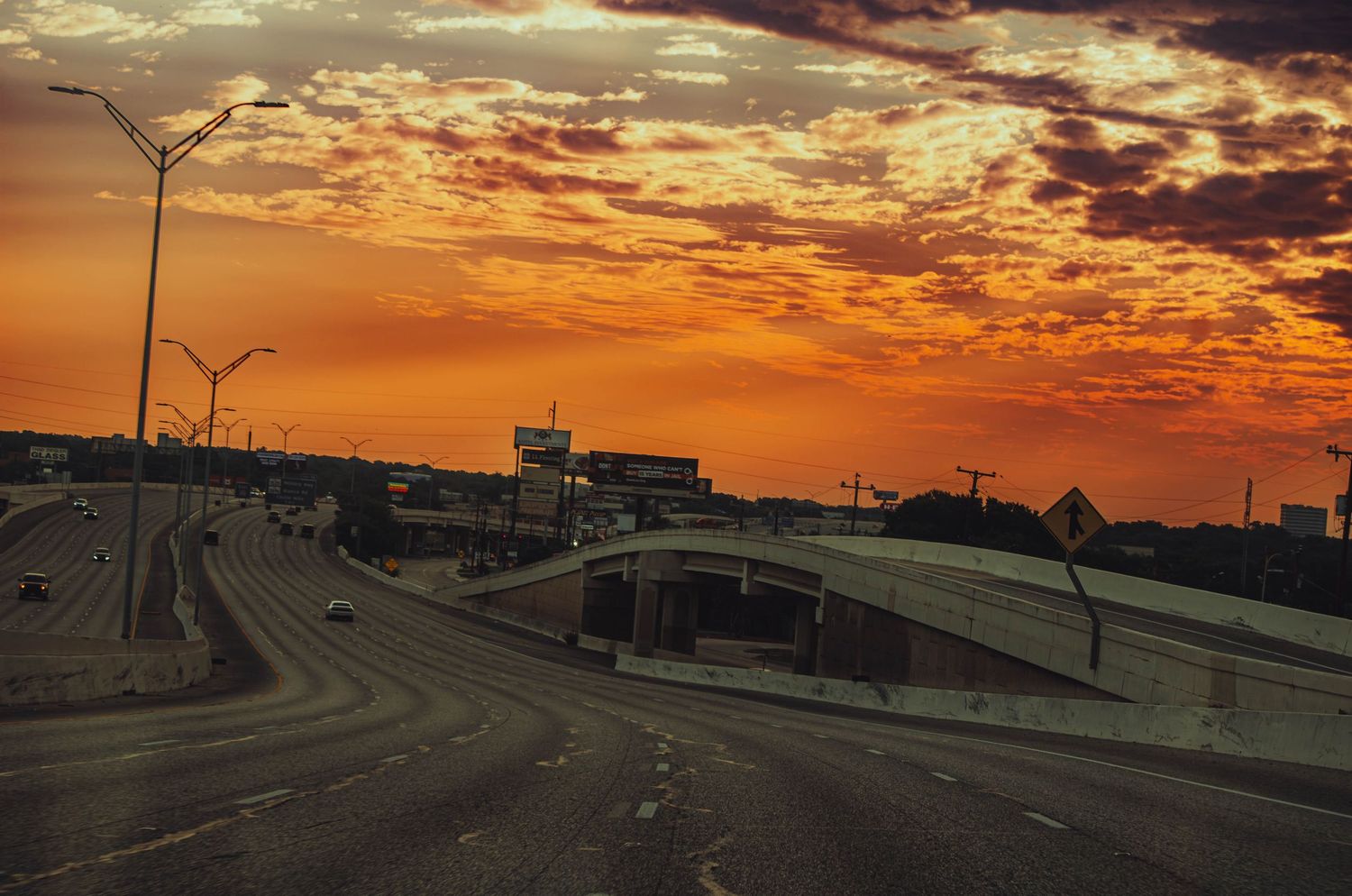 Dramatic orange sunset sky over an empty urban highway overpass at dusk.