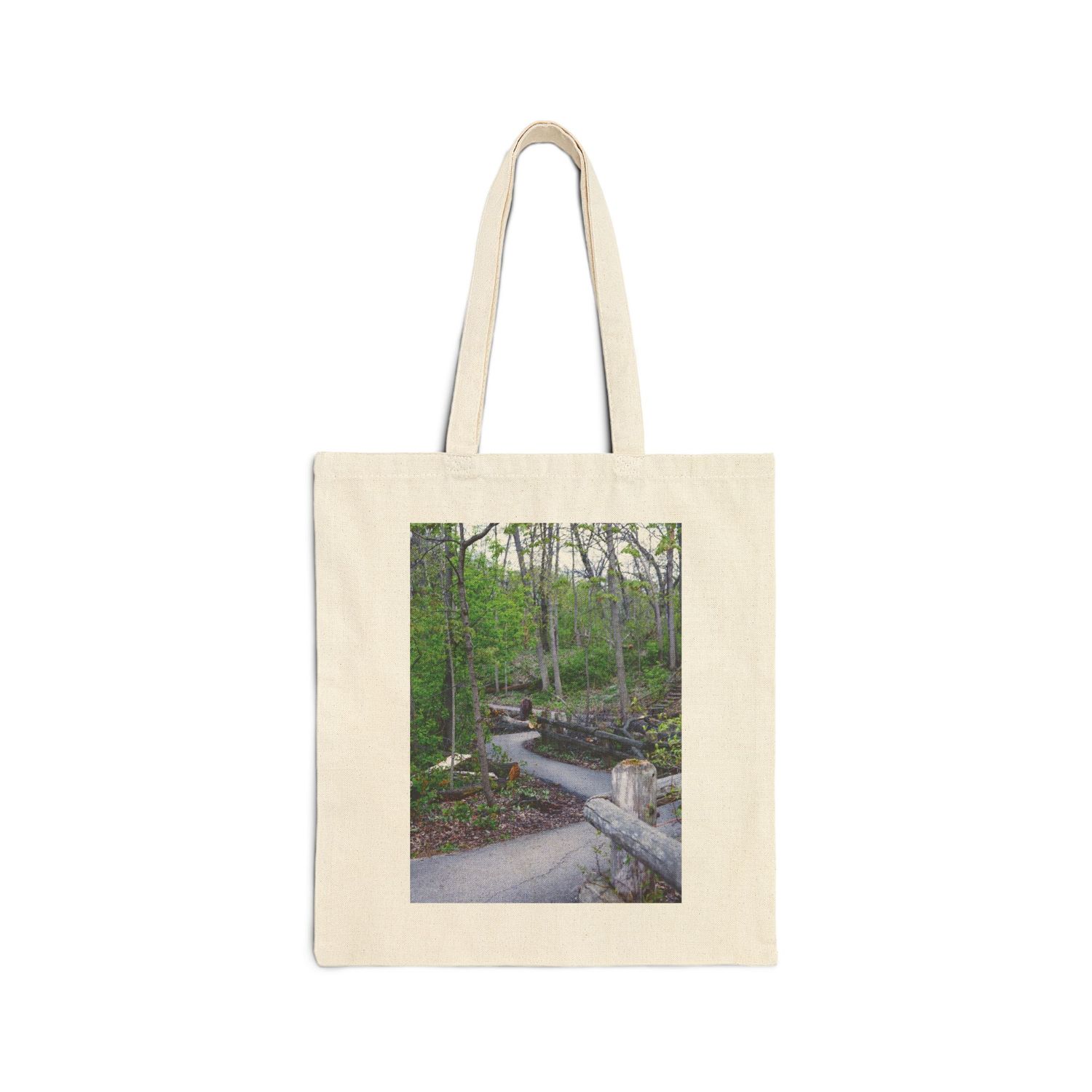 Canvas tote bag featuring a winding forest path with stone walls and lush green trees printed on the front.