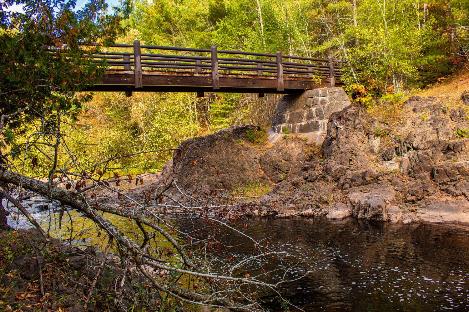 Wooden bridge over rocky river in a forested park