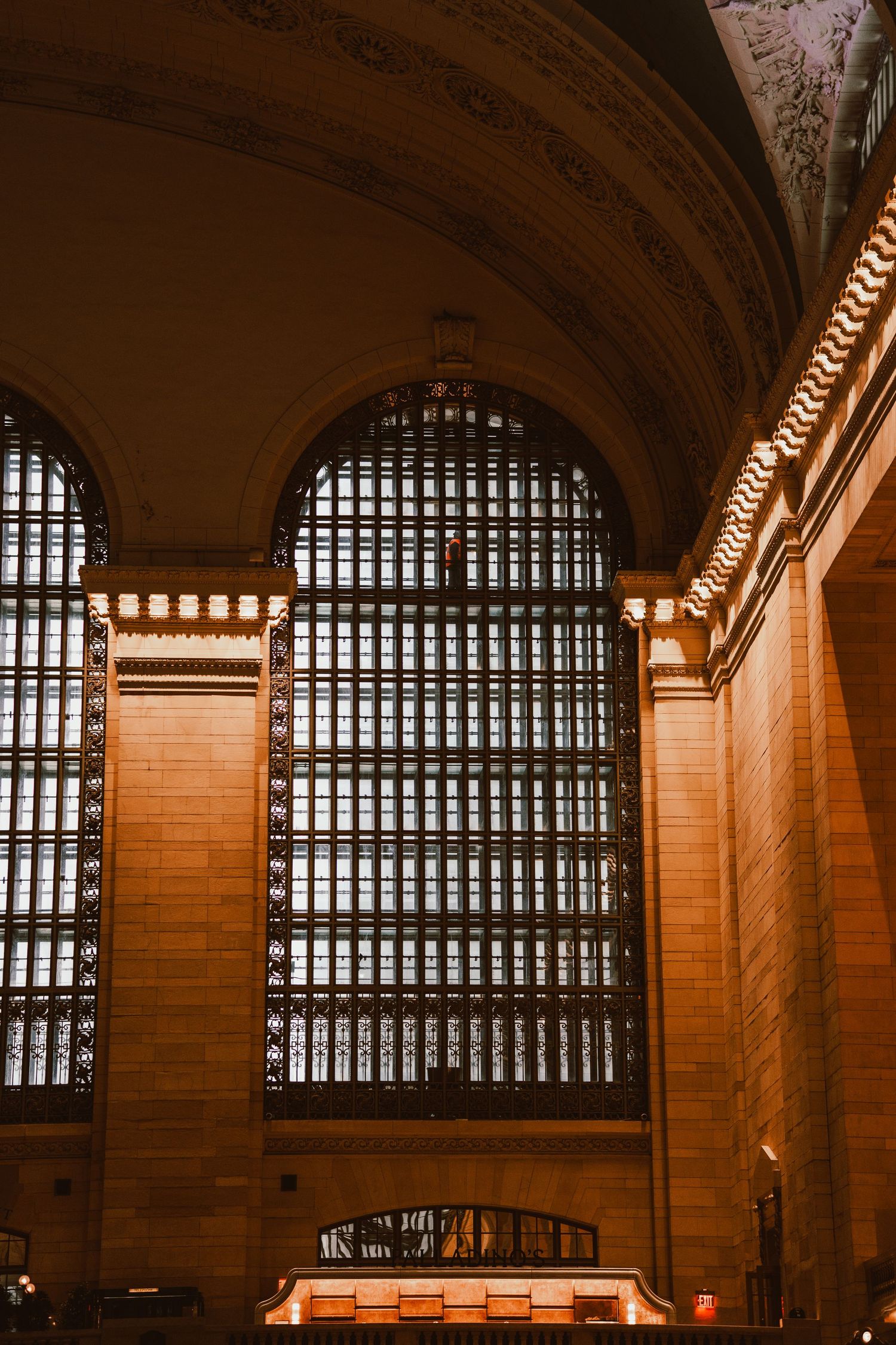 Grand arched windows illuminating ornate interior of Grand Central Terminal.