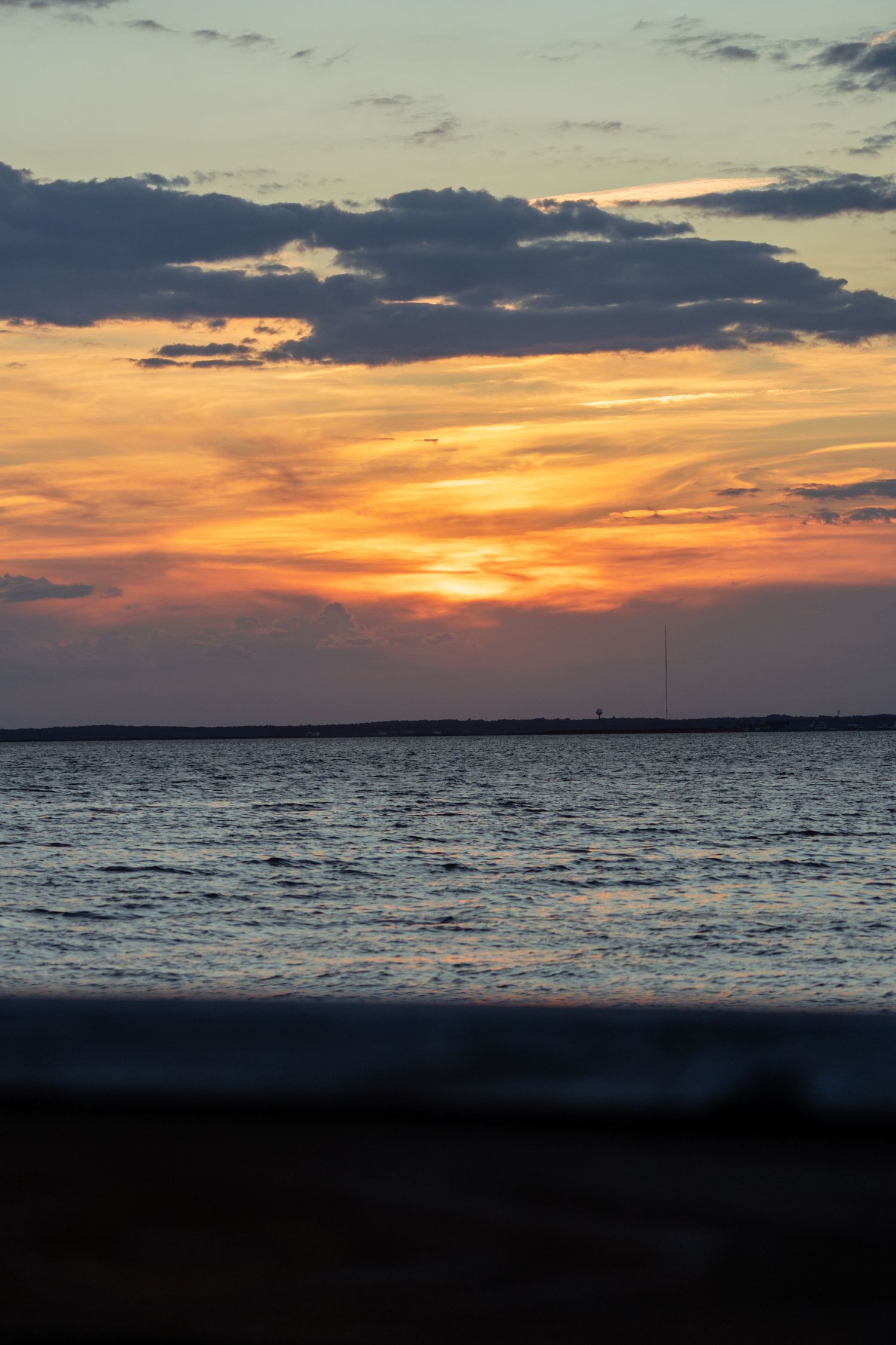 Vibrant orange and purple sunset over calm ocean waters with dramatic clouds on the horizon.