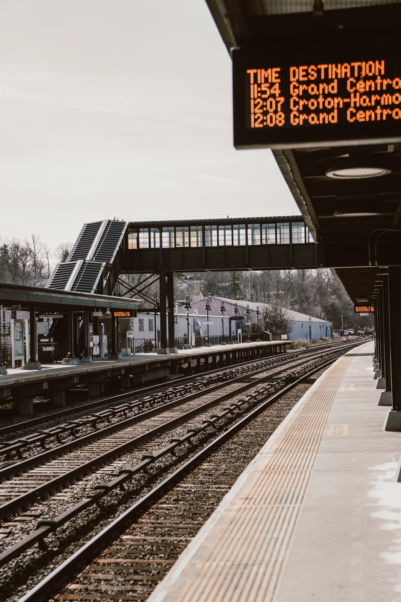 Commuter rail platform with departure board showing Grand Central and Croton-Harmon train times.