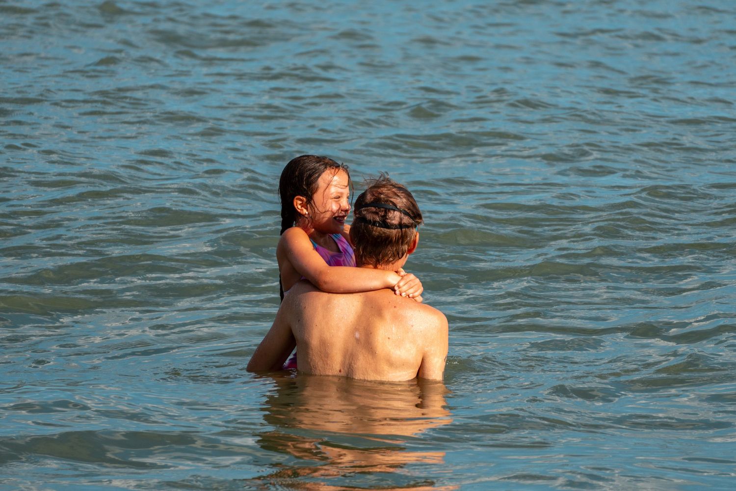 Couple hugging and smiling in the ocean water on a bright sunny day.