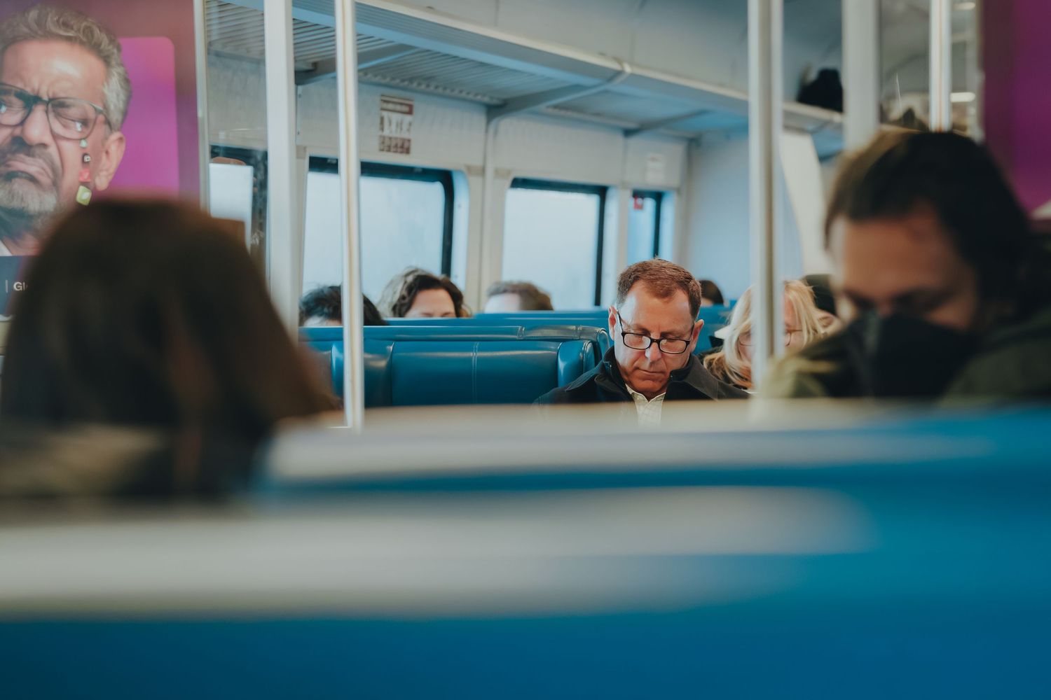 Passengers sitting in blue seats on a commuter train.