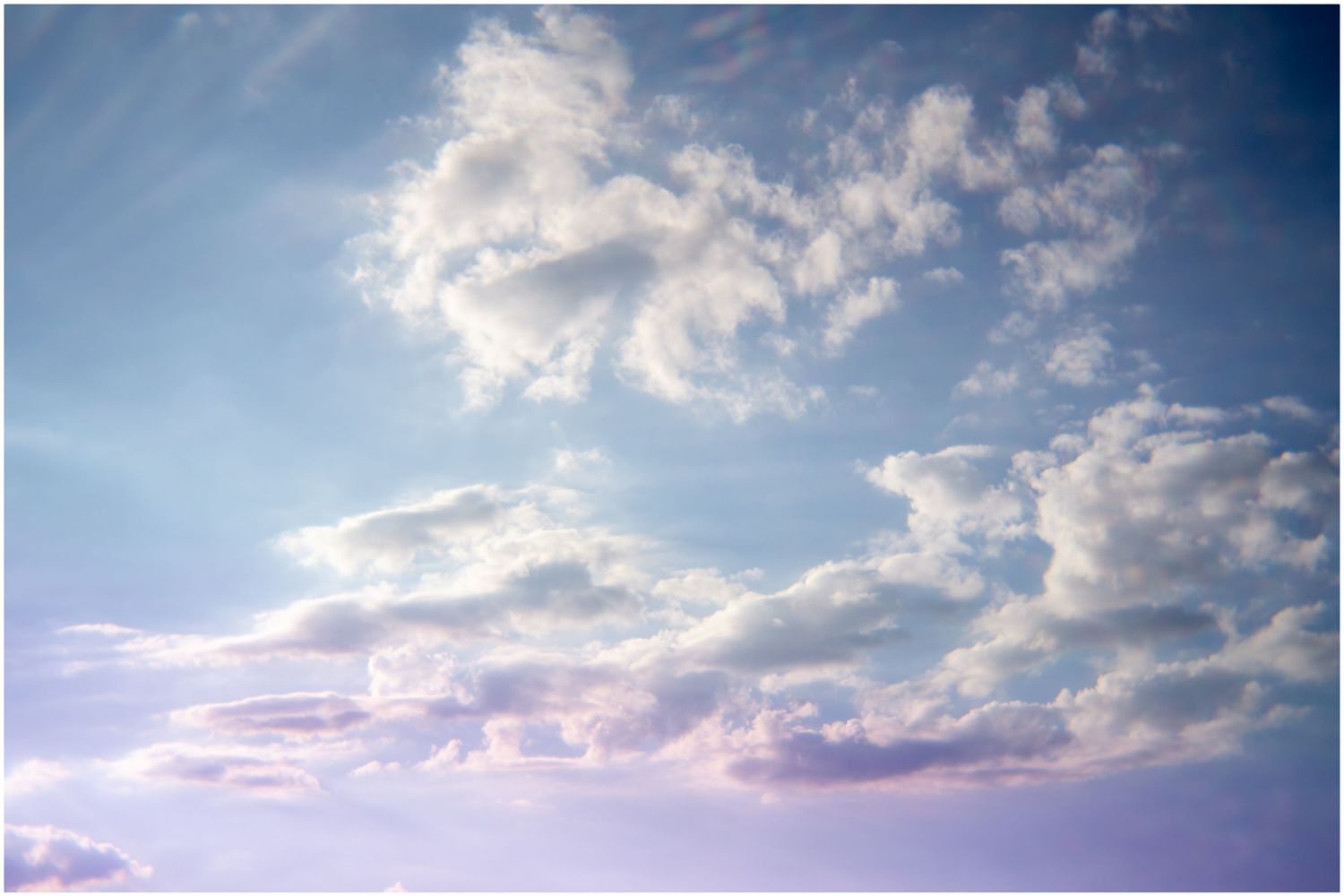 Dramatic sky with billowing white clouds against a soft blue and purple gradient backdrop.