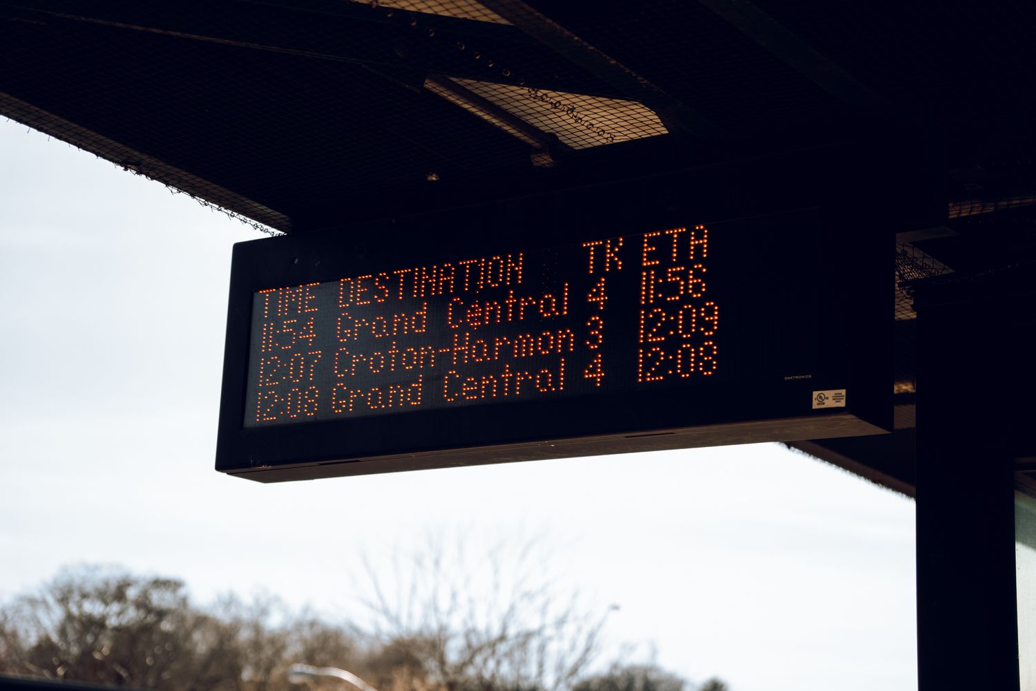 Train station departure board showing Grand Central and Croton-Harmon destinations with ETAs.