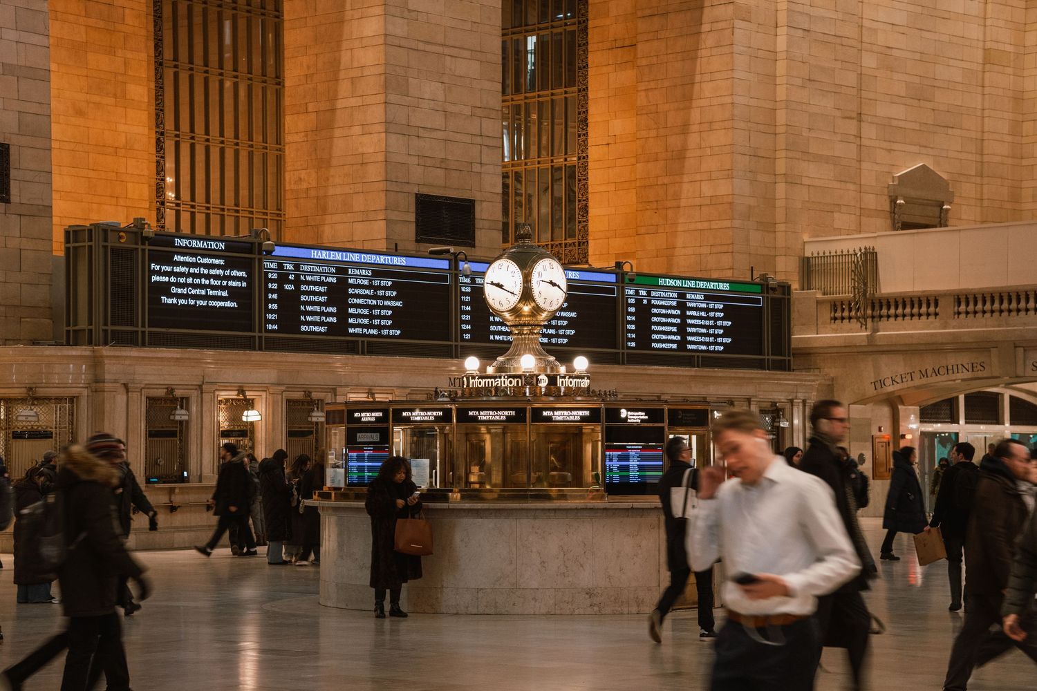 Busy Grand Central Terminal main concourse with departure boards and iconic gold clock above the information booth.