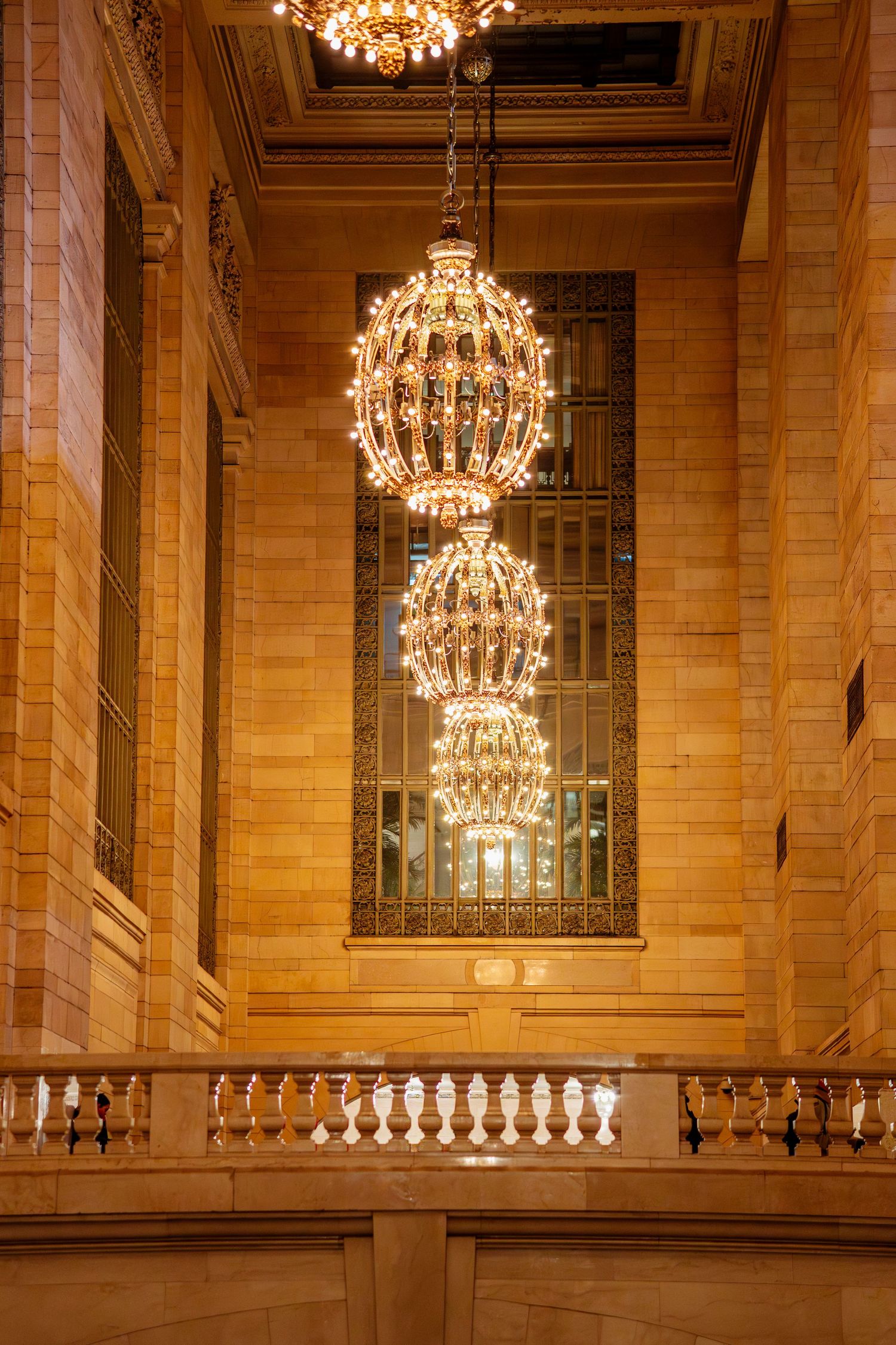 Elegant ornate chandeliers hanging from the ceiling of Grand Central Terminal illuminating the grand interior.