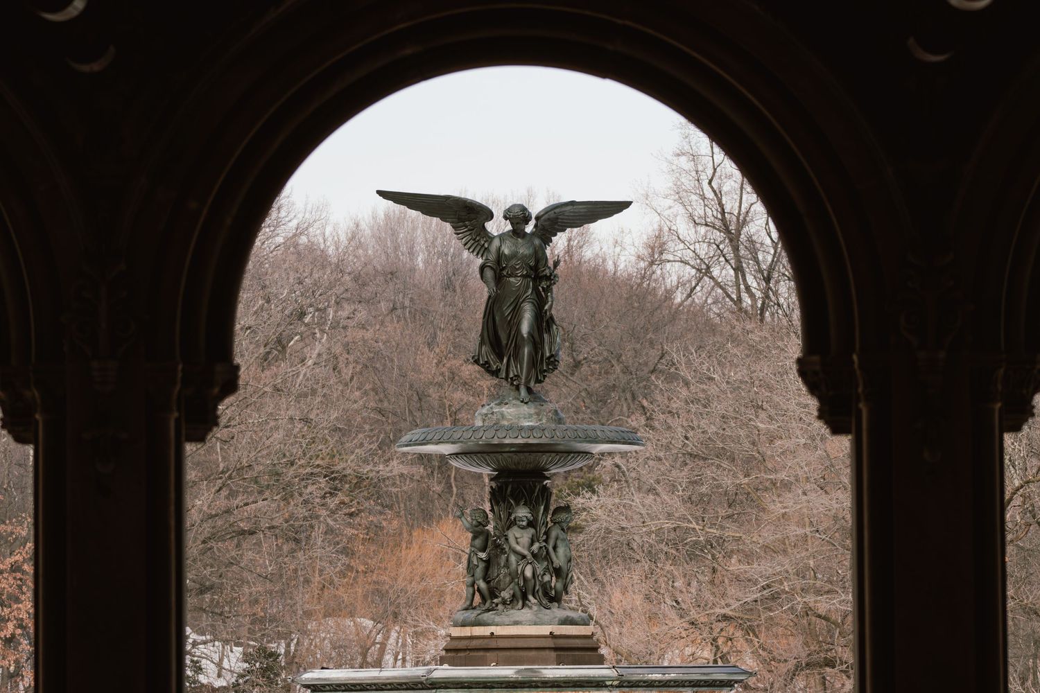 The Bethesda Fountain angel statue framed by a stone arch in Central Park, New York City.