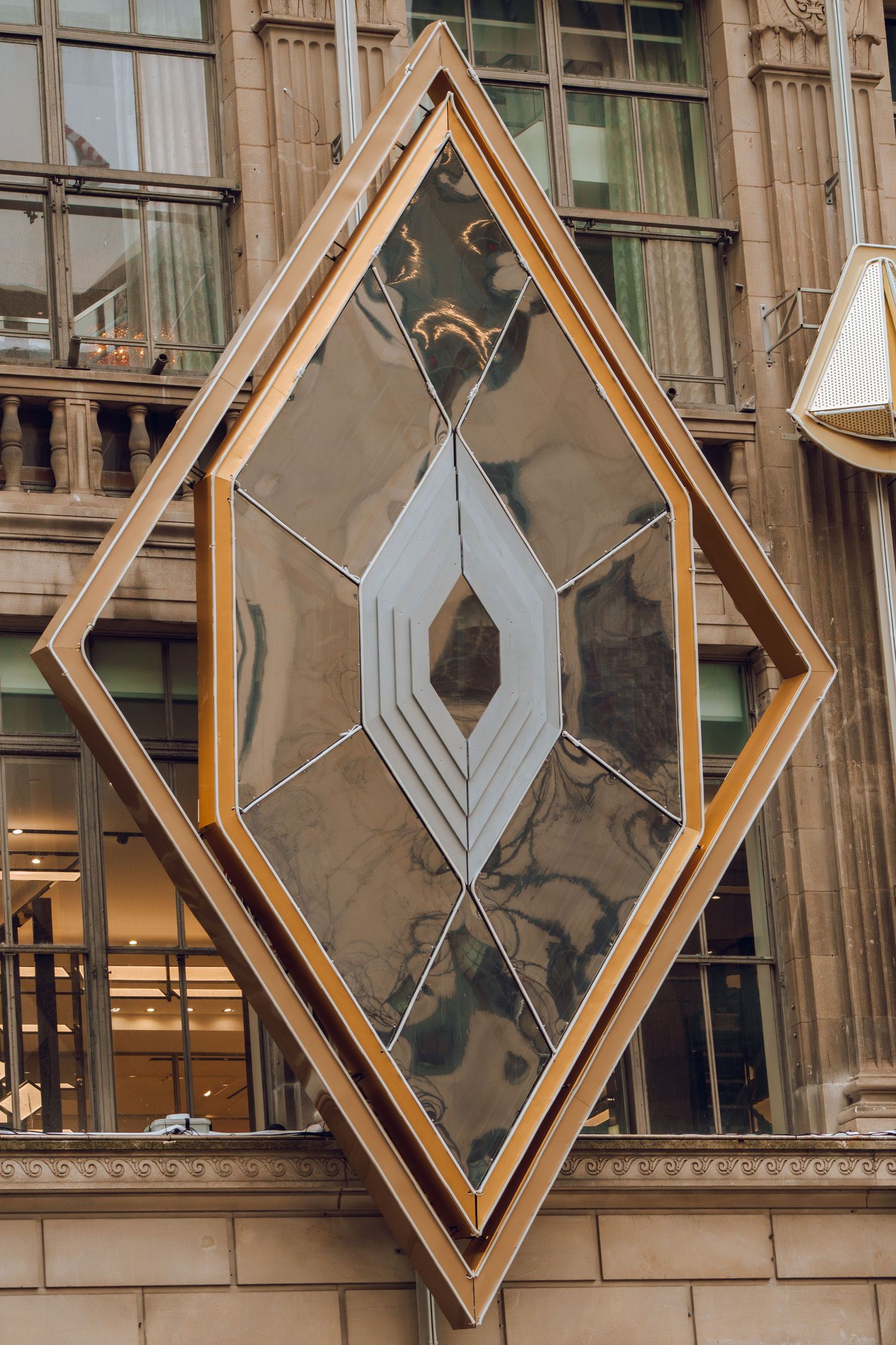 Art Deco diamond-shaped decorative mirror installation on a classic stone building facade in New York City.