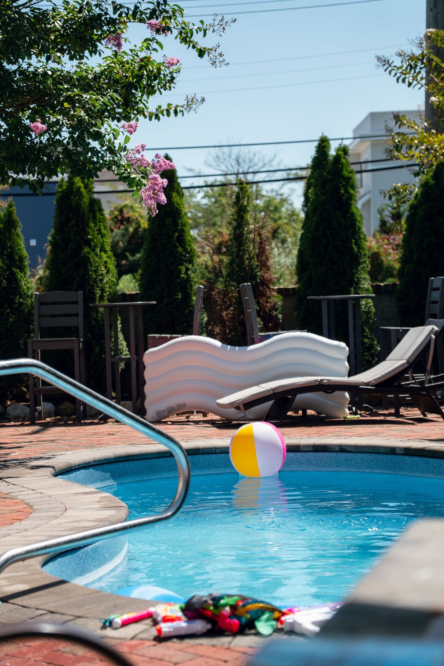 Backyard swimming pool with a colorful beach ball, inflatable float, and lounge chairs.