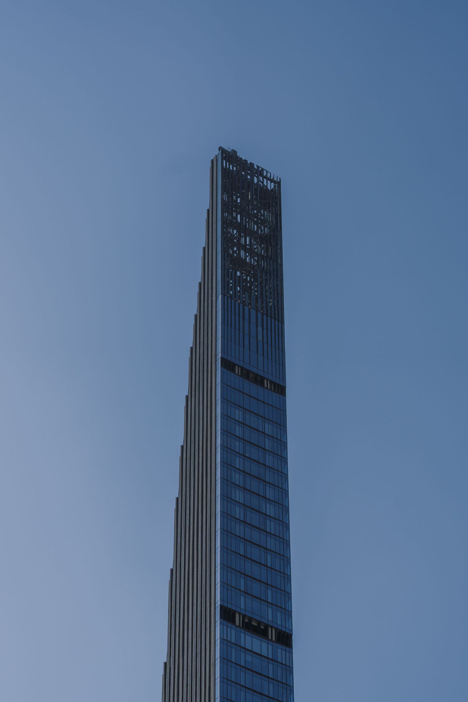 Modern glass skyscraper tower reaching into a clear blue sky.