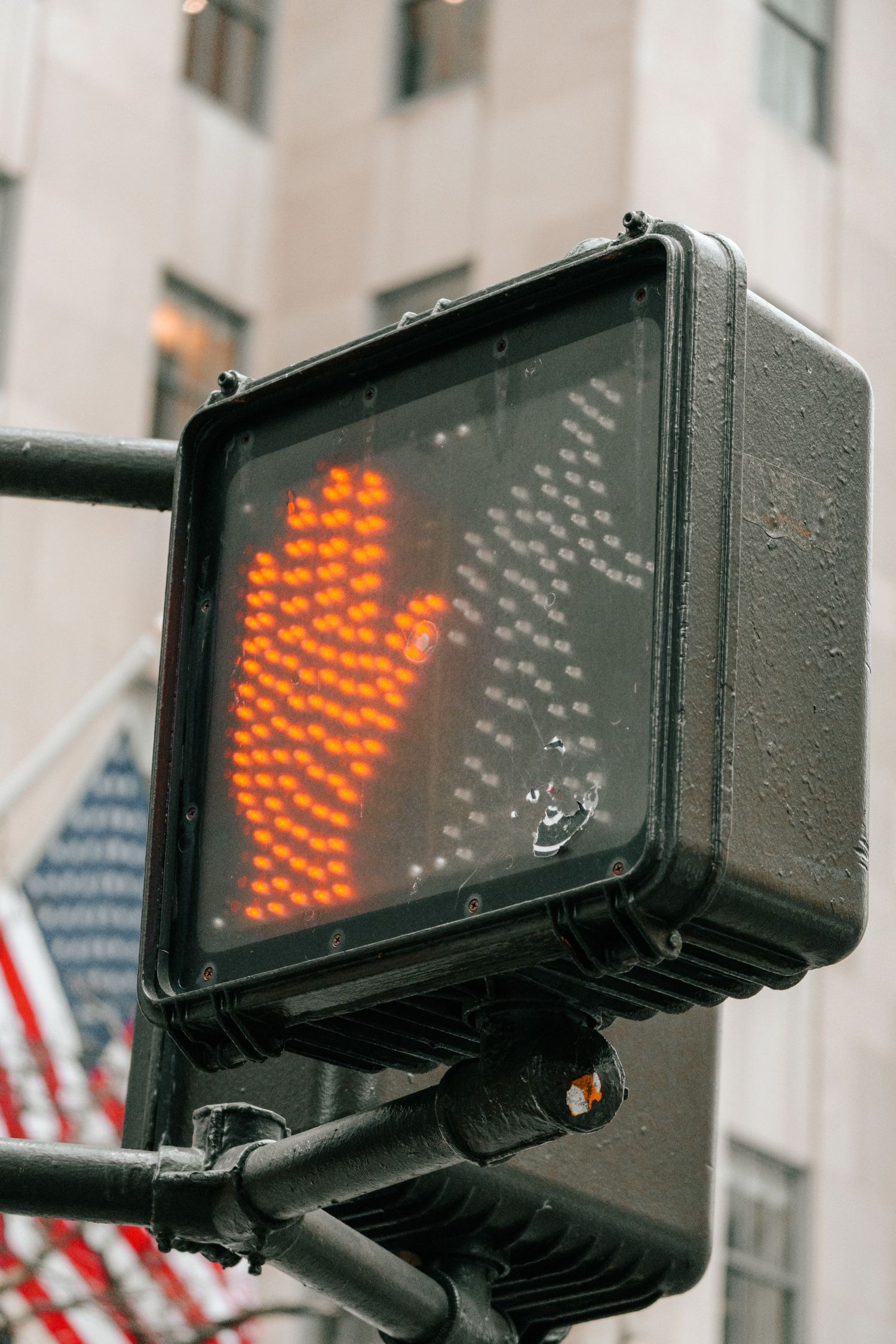 Orange illuminated stop hand pedestrian traffic signal light mounted on pole in New York City.