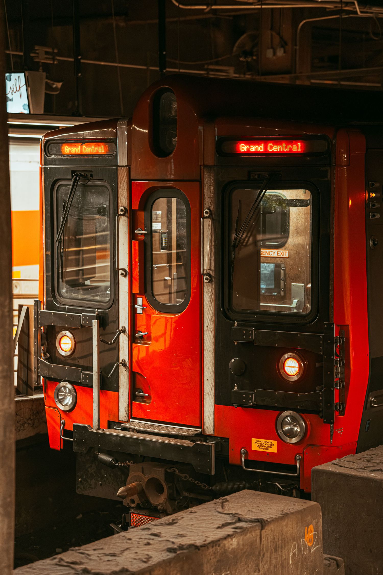 A red Metro-North commuter train displays Grand Central destination sign at a terminal platform.