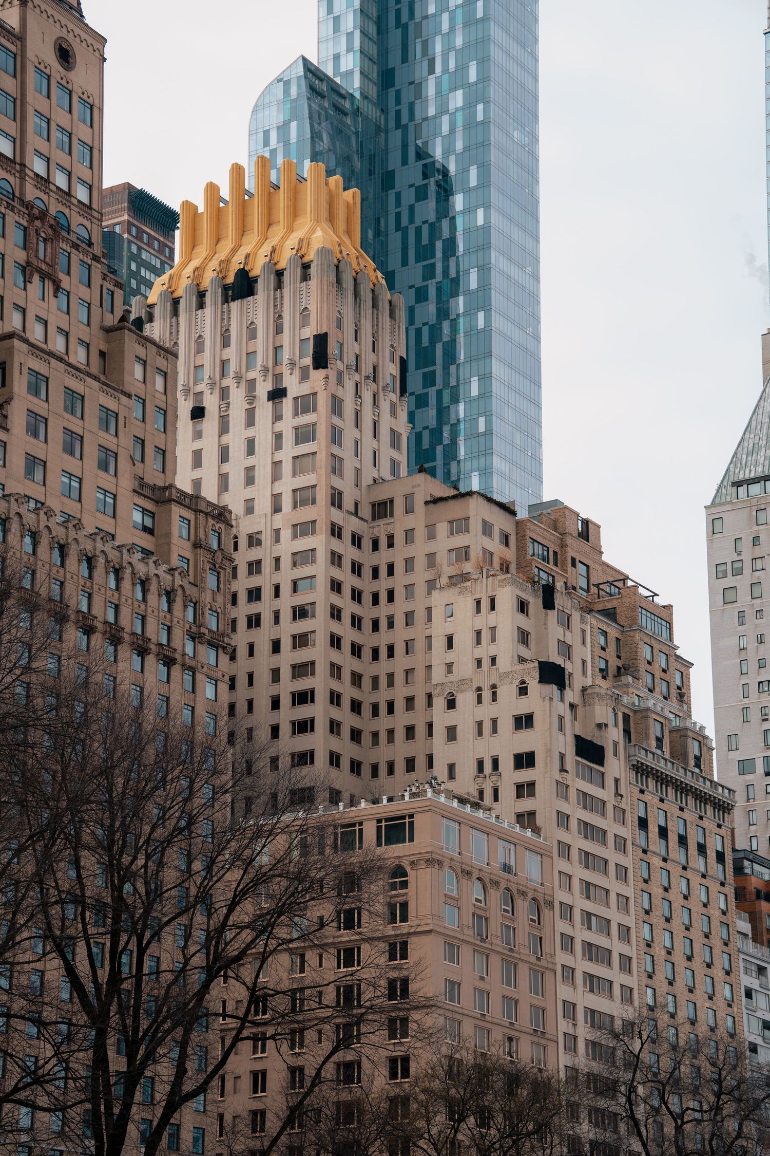 Art Deco skyscraper with golden crown detail alongside modern glass tower in New York City.